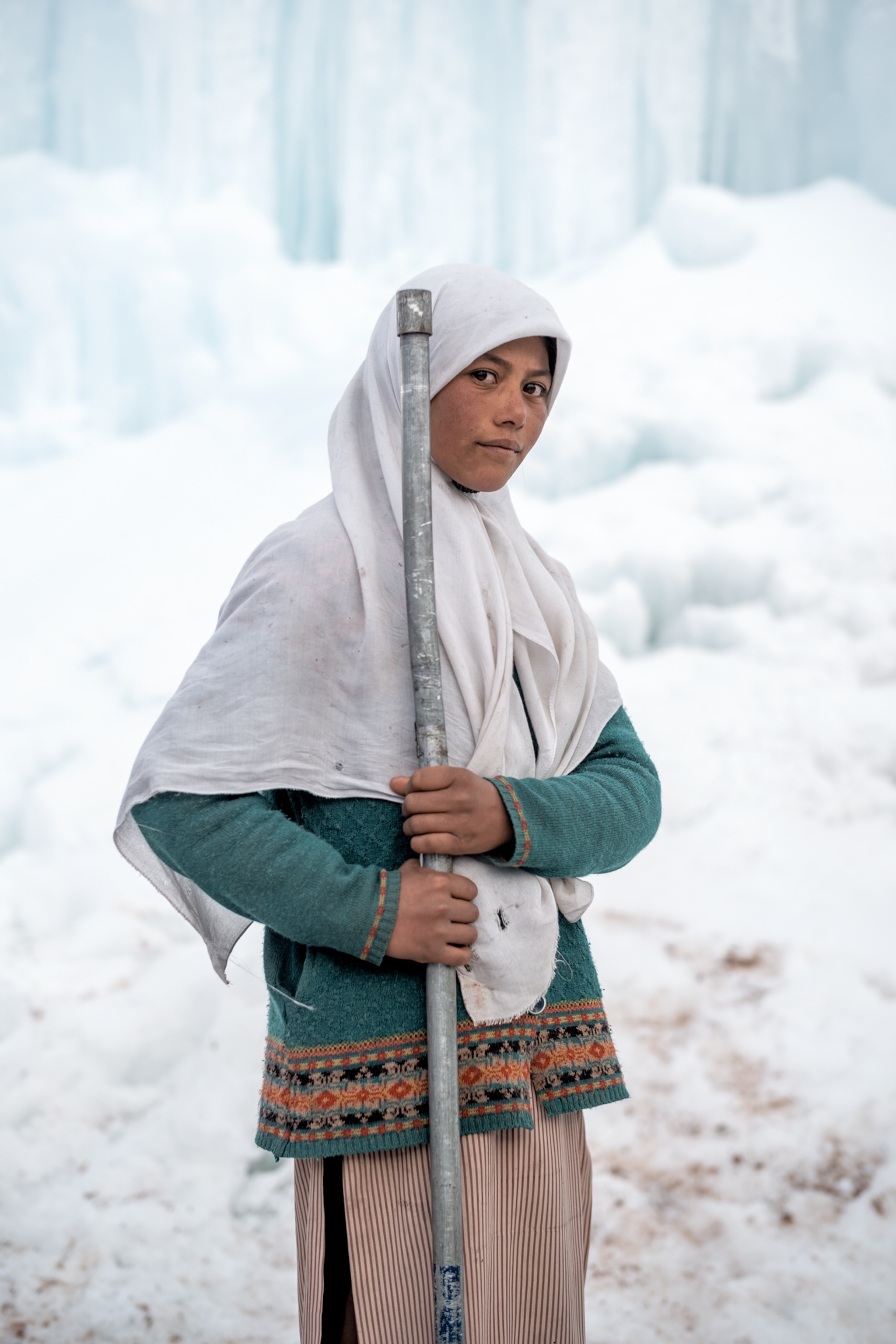 girl in white head covering with metal pipe.