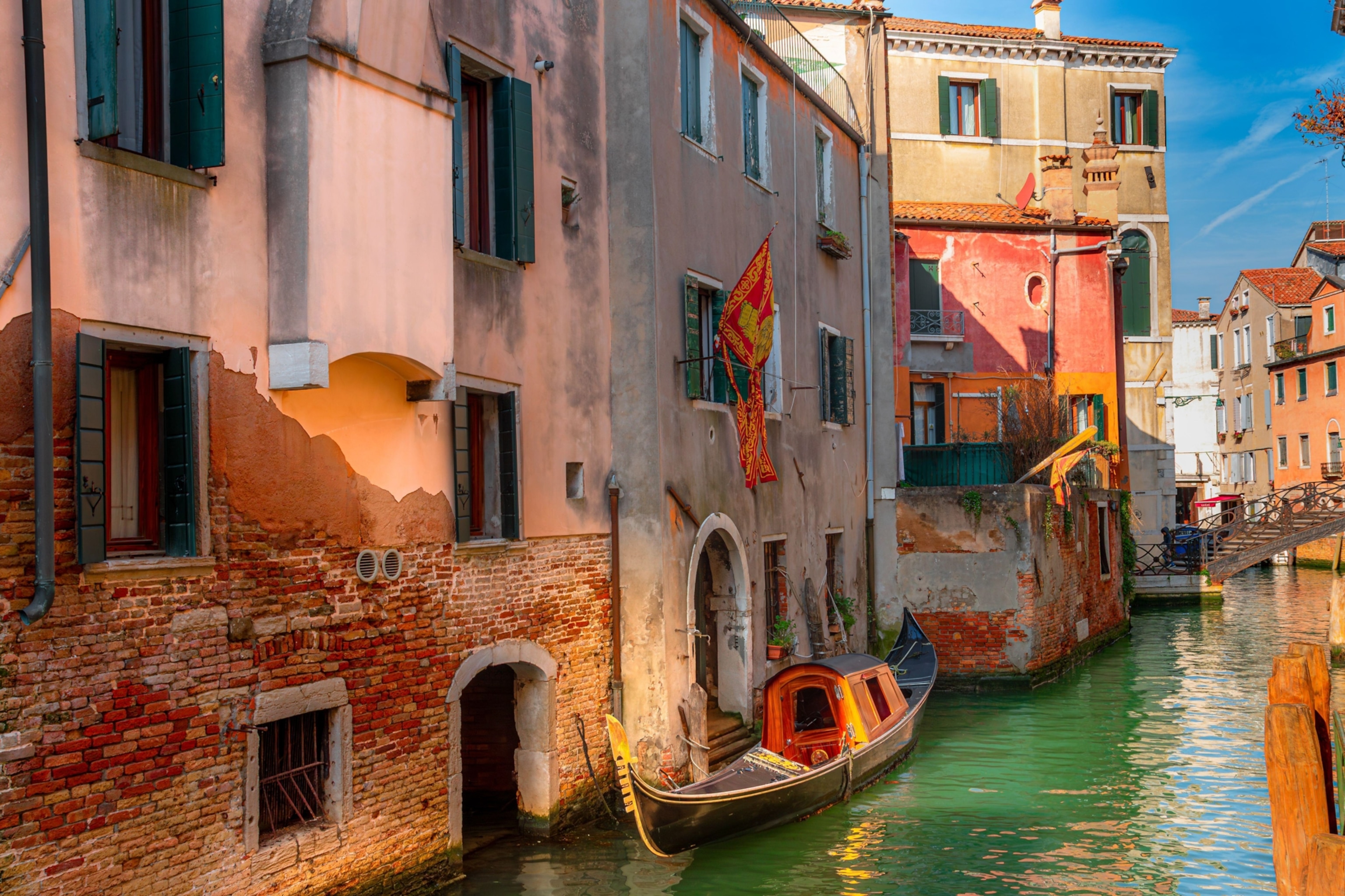 An old gondola resting atop light green waters of a canal in Venice.