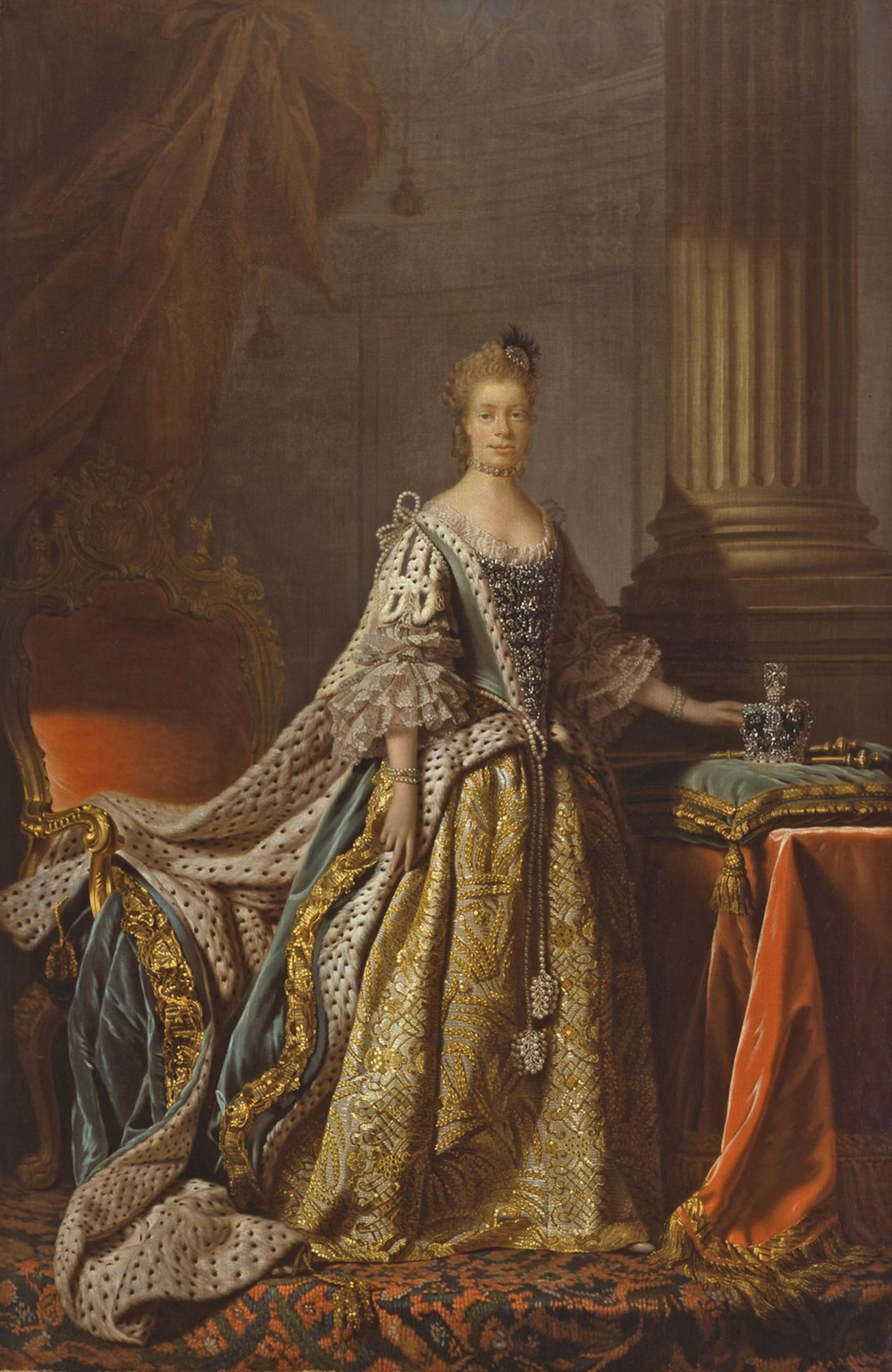The queen stands hand placed on crown gaze affixed on the viewer.