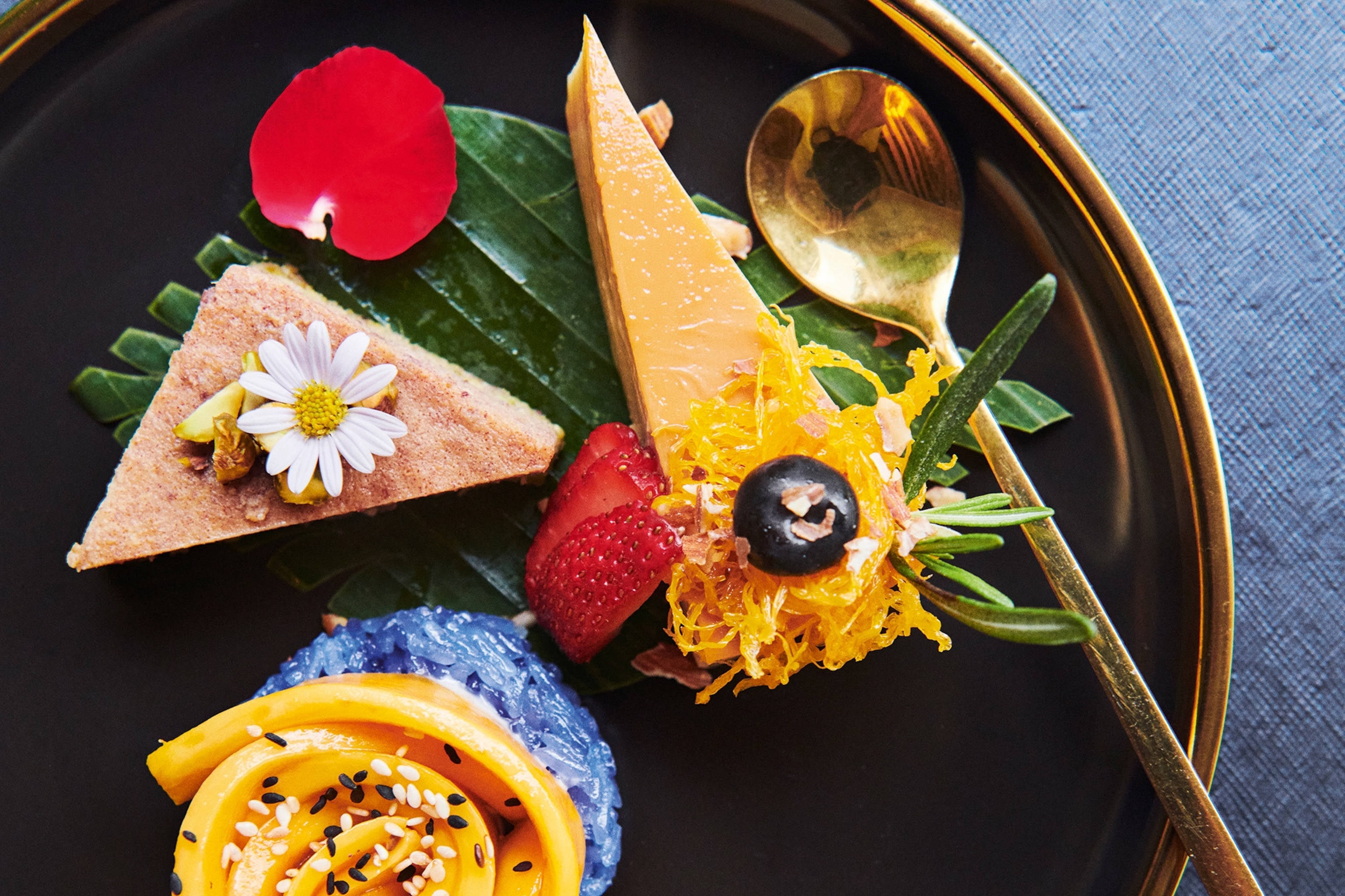 A black plate with a yellow rim holds colourful desserts using exotic fruits in Thailand.