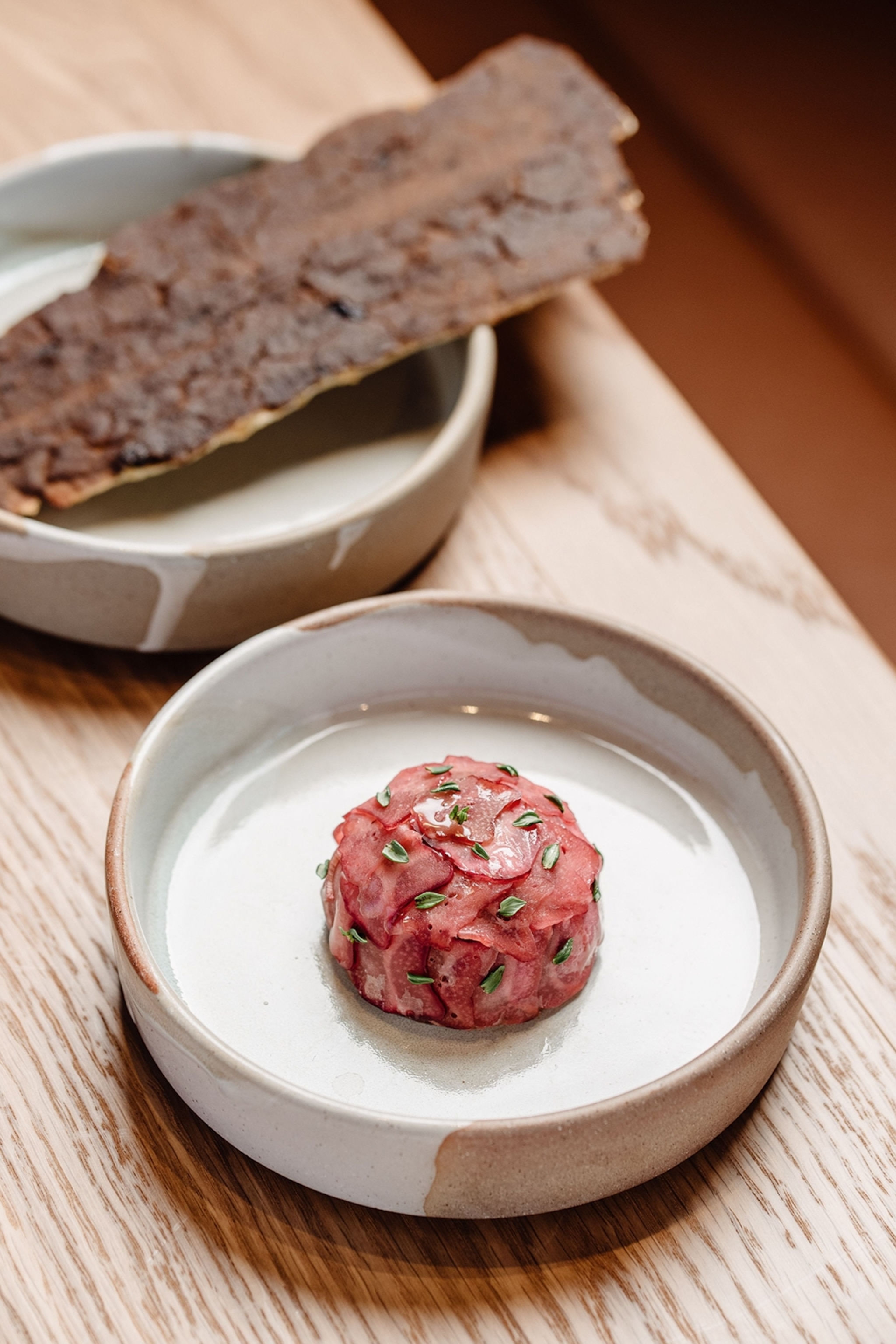 A tall rimmed white round plate with a spherical dish of chicken liver and radishes.