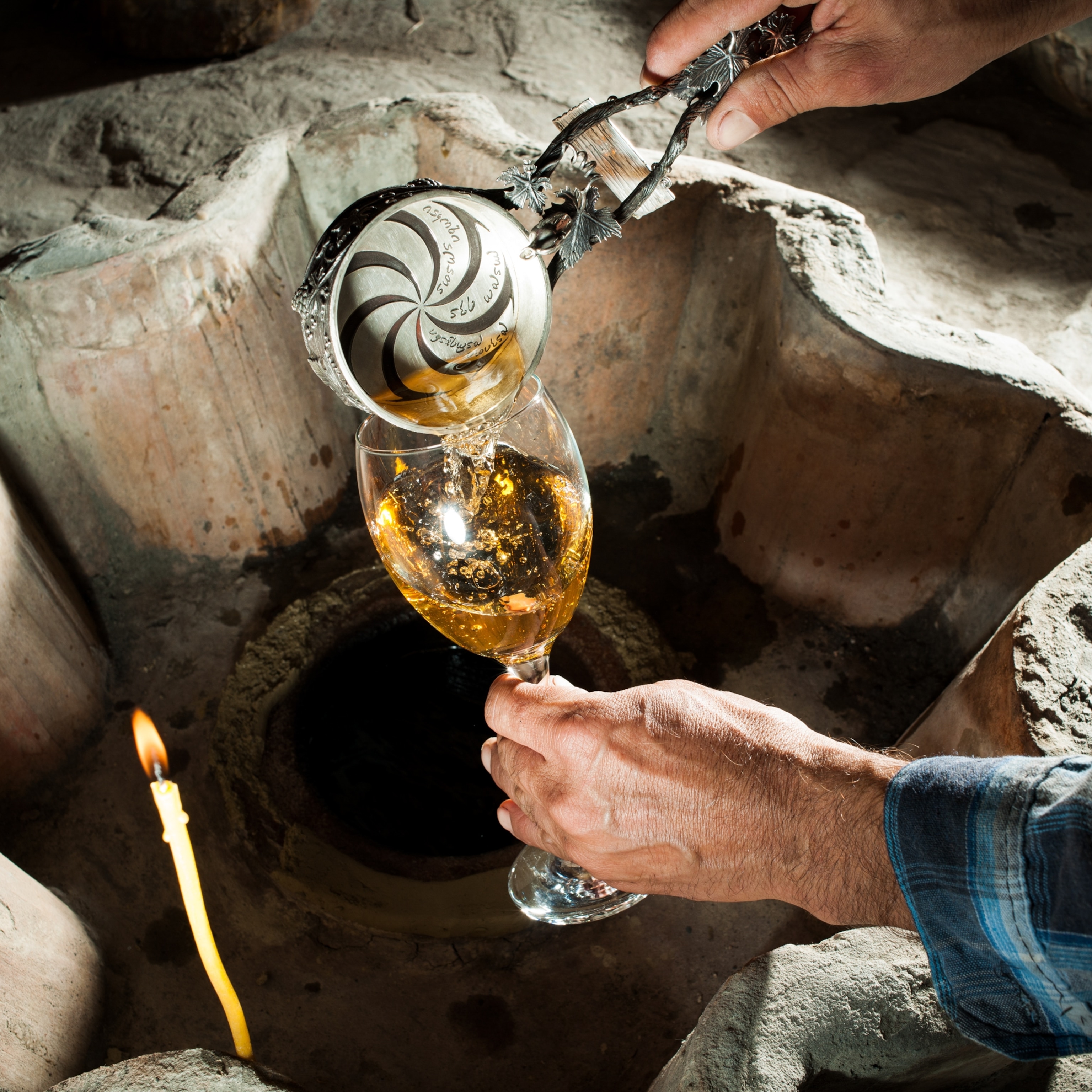 a man pouring wine into a glass with a ladle