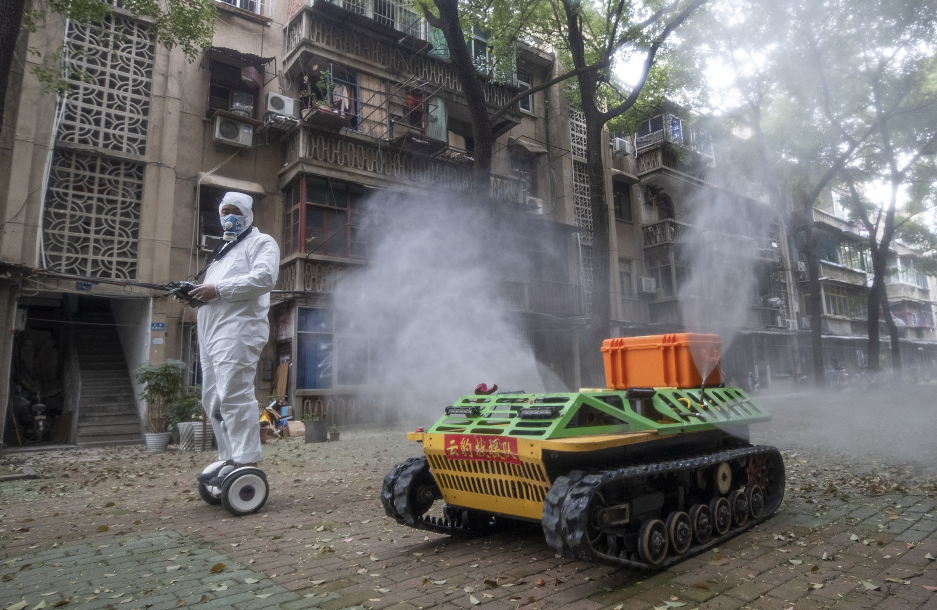 a person scootering next to a automated truck spraying disinfectant