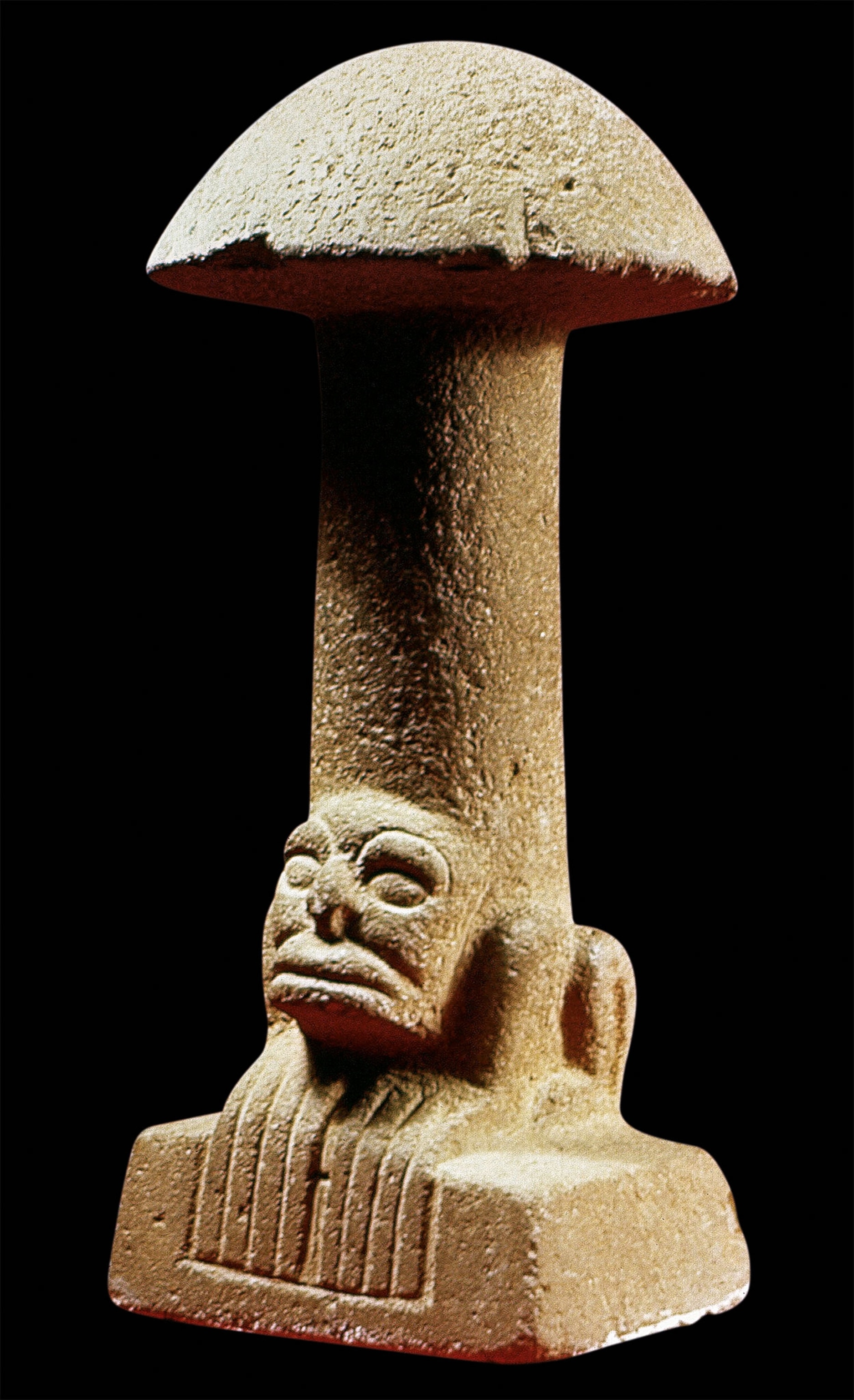 A stone sculpture of a mushroom with a face at the bottom