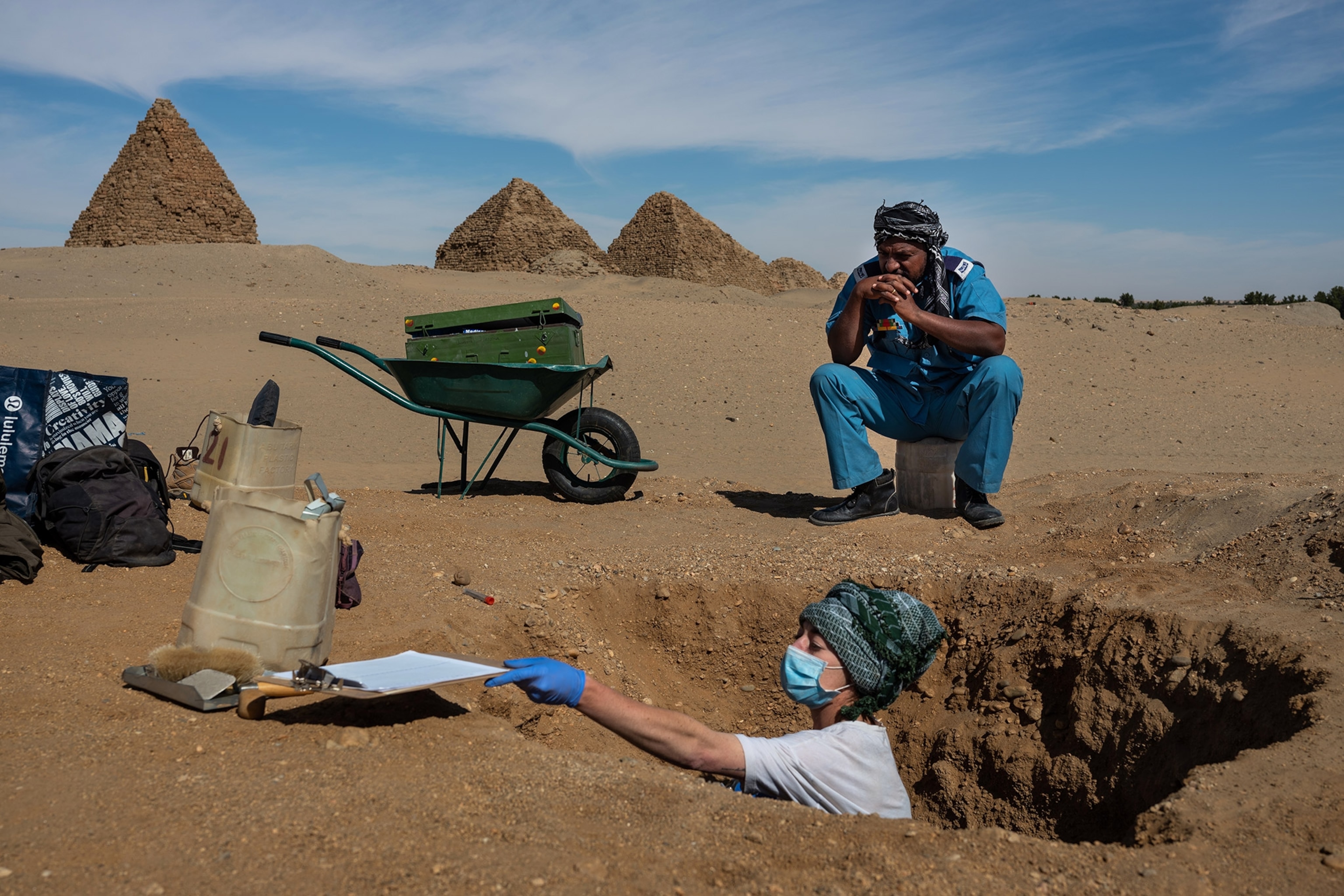 Archeologist Gretchen Emma Zoeller excavates a Meroitic-style burial site of an adult female as Tourism and Antiquities police officer Mohamed Halifa Khalid looks on in Nuri, Sudan