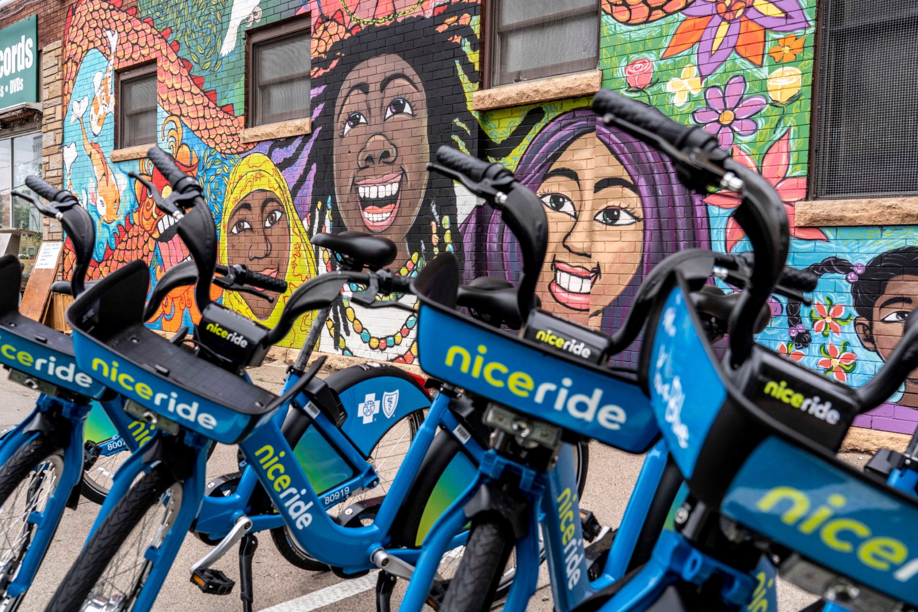 Bikes for rent seen in front of a colorful mural with peopl