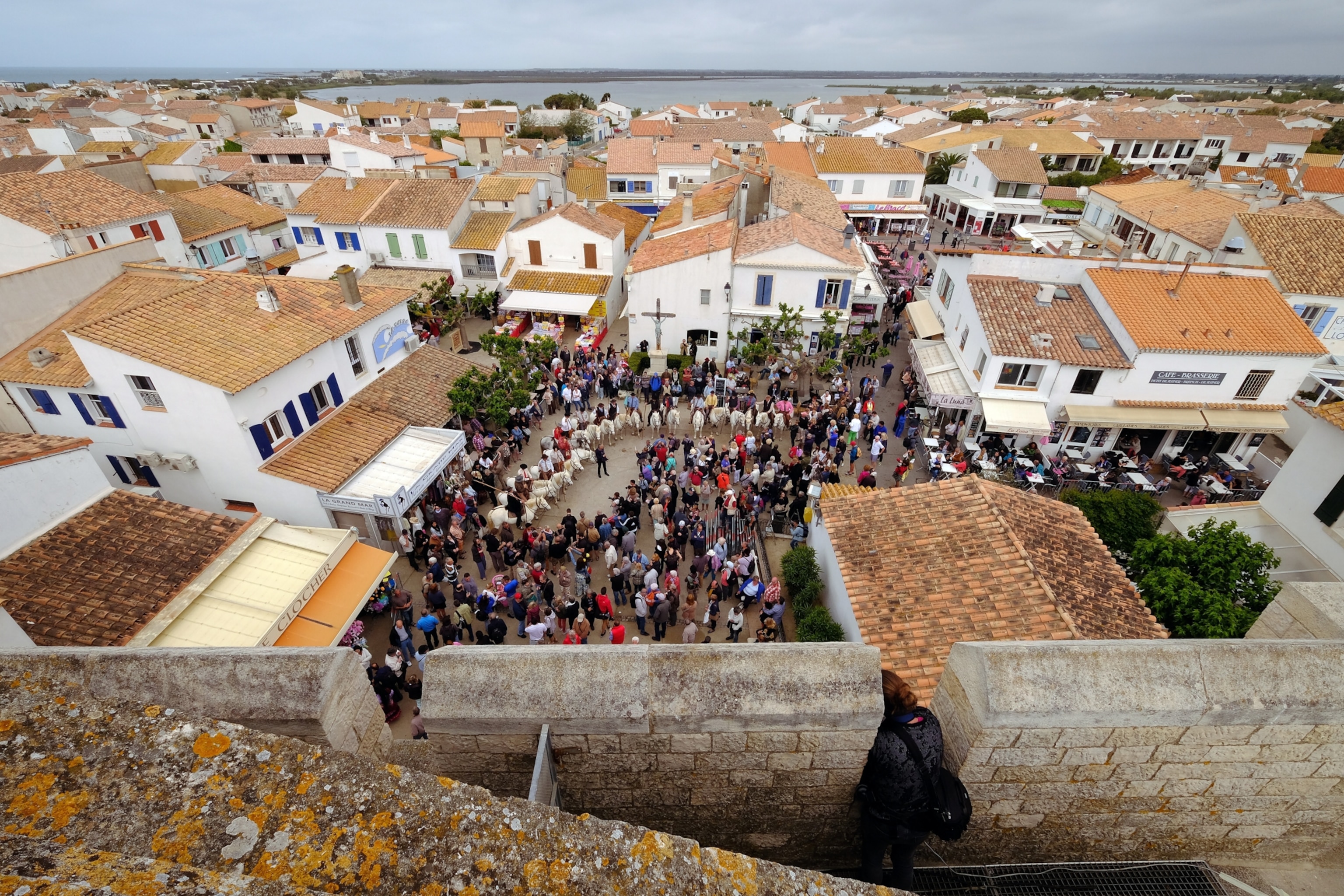 A view looking own into the courtyard in front of Saintes Maries de la Mer church, where horsemen and pilgrims have gathered for a procession to the sea.