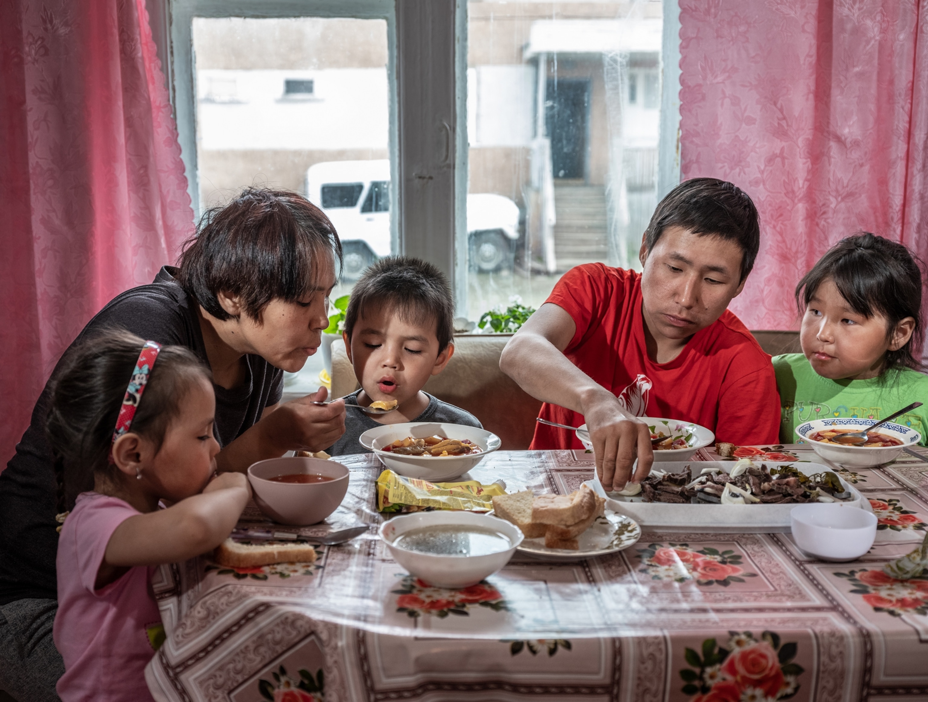 woman, man and tree children at the table having meal.