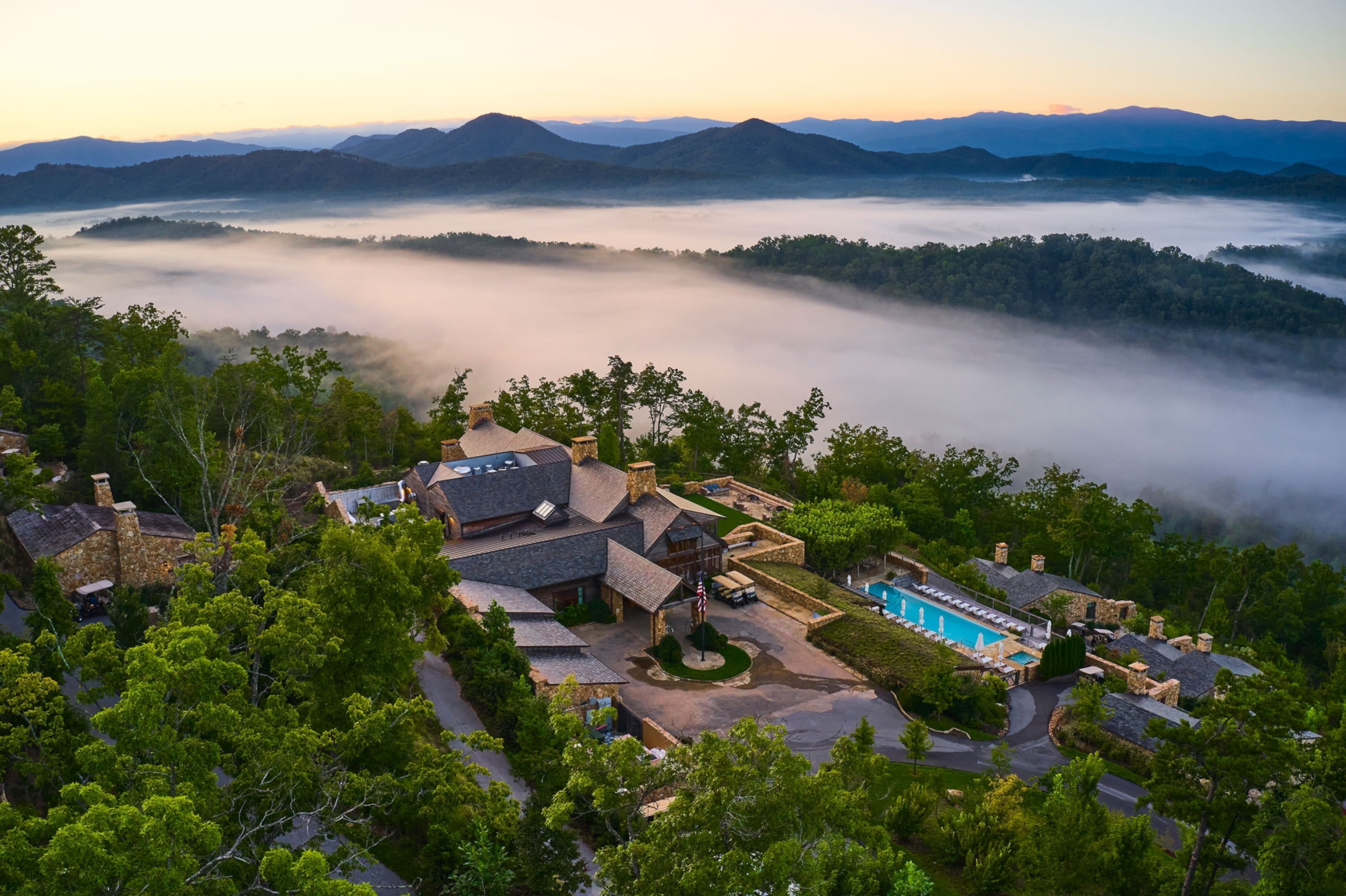An overhead drone view of the Blackberry Mountain lodge surrounded by mountains and fog