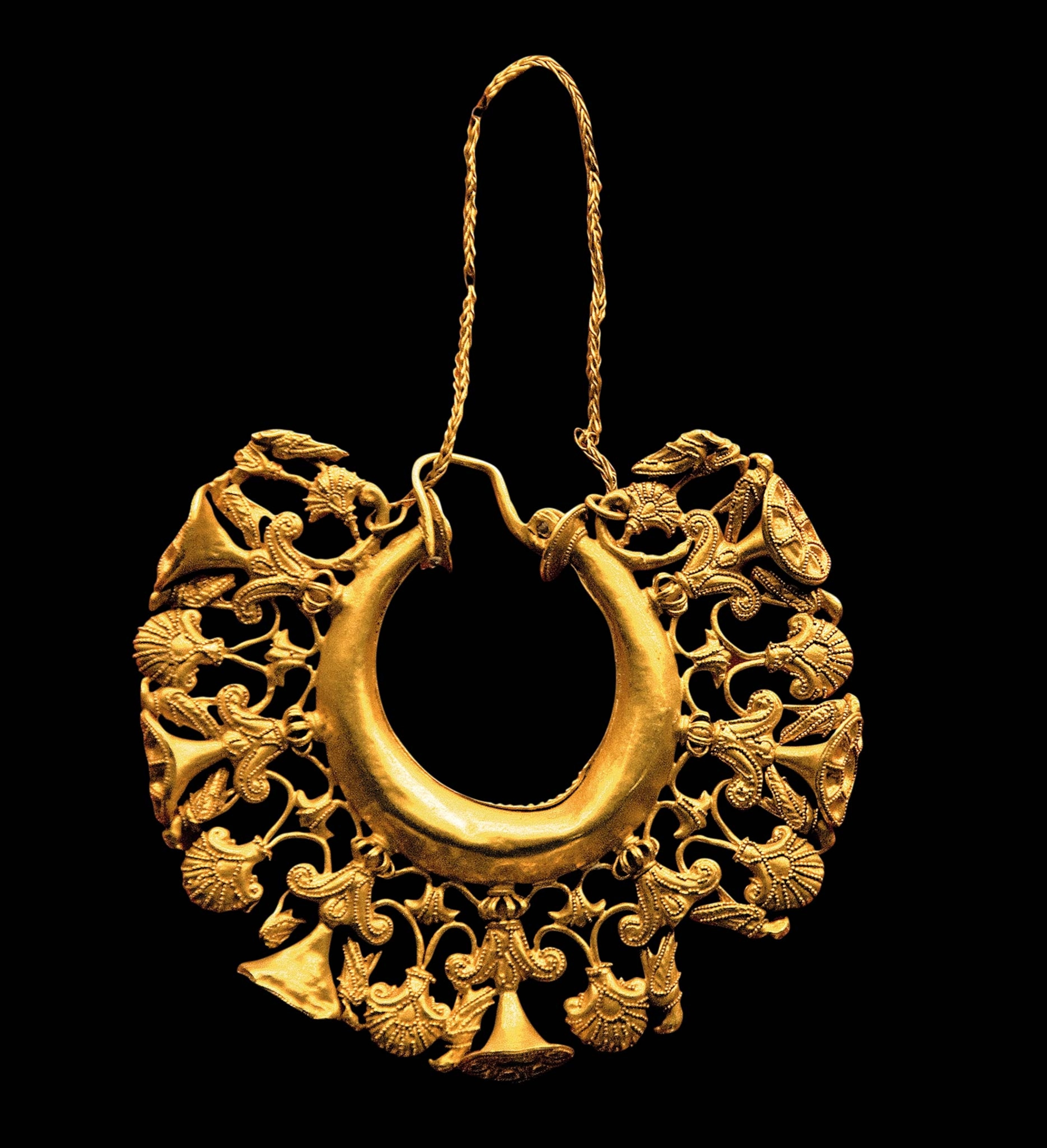 A gold earring is exuberantly decorated with lotus flowers, palmettes, and falcons