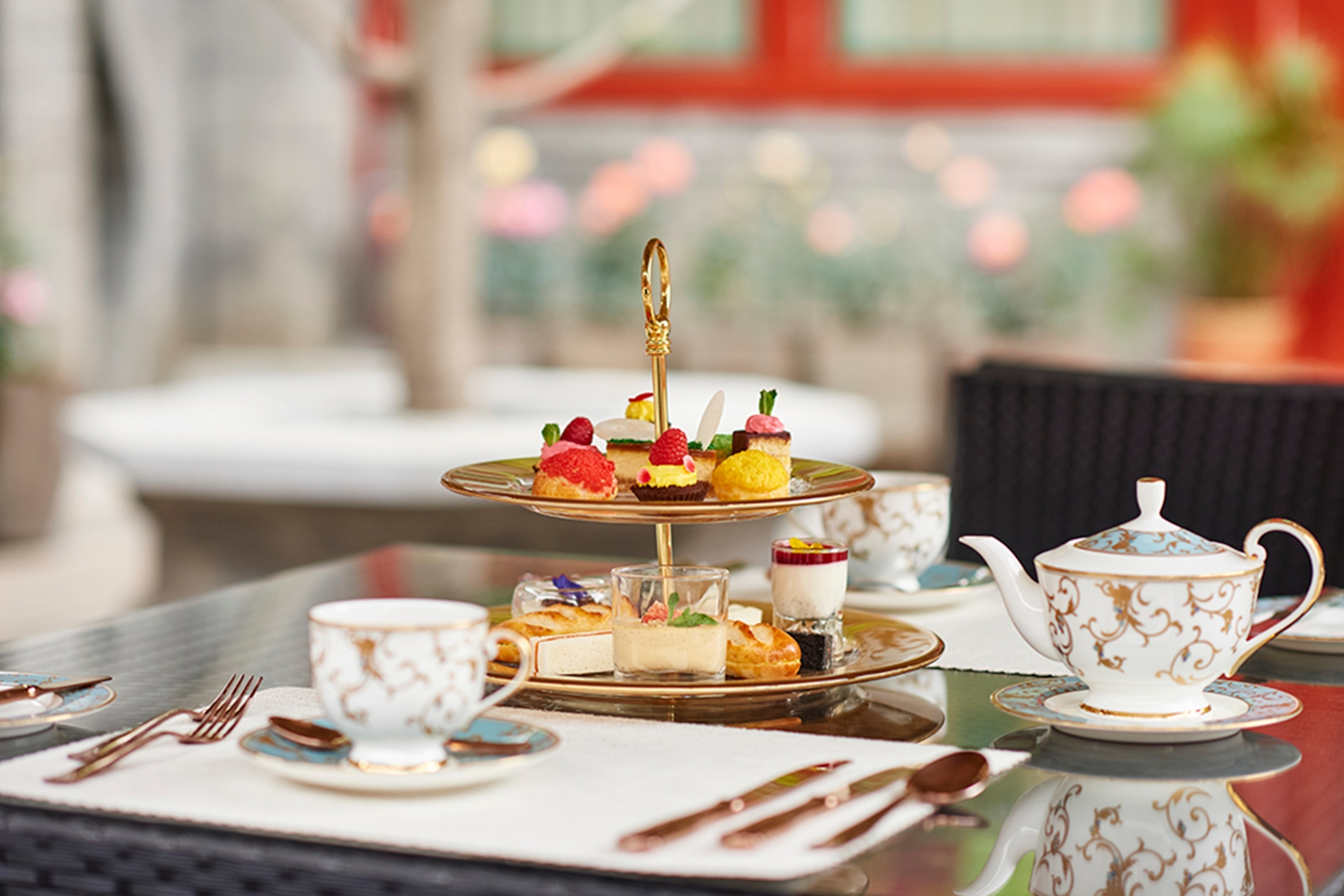 Afternoon tea served on a tiered plate stand with teapots and cups