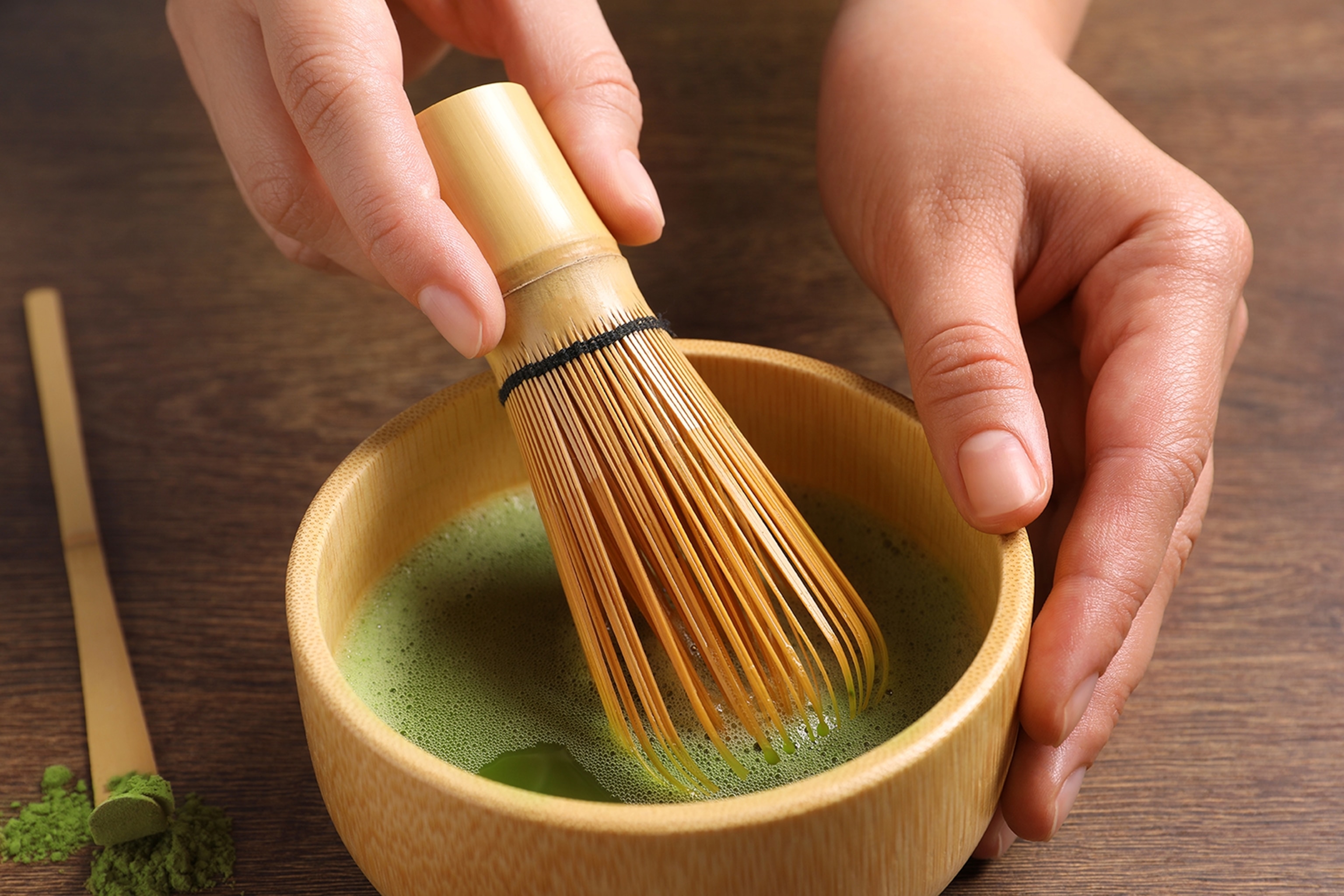 Woman preparing matcha tea at wooden table