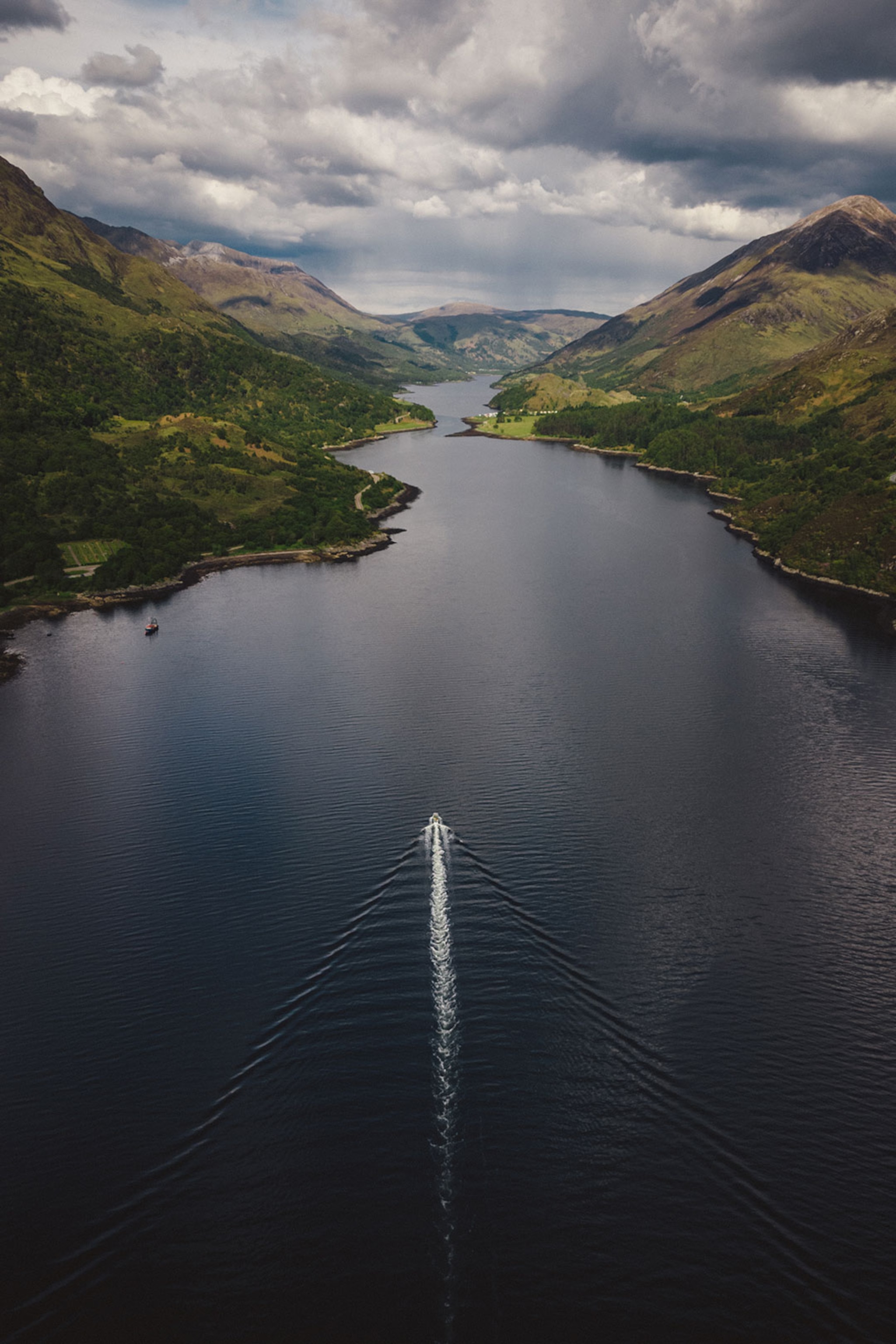 A birds-eye view of a dark lake with a small boat.