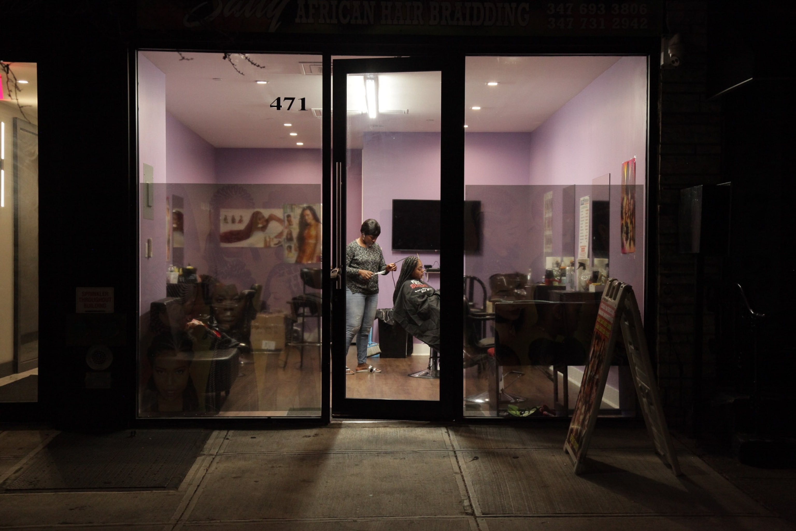 a woman standing in a salon near the doorway at night time