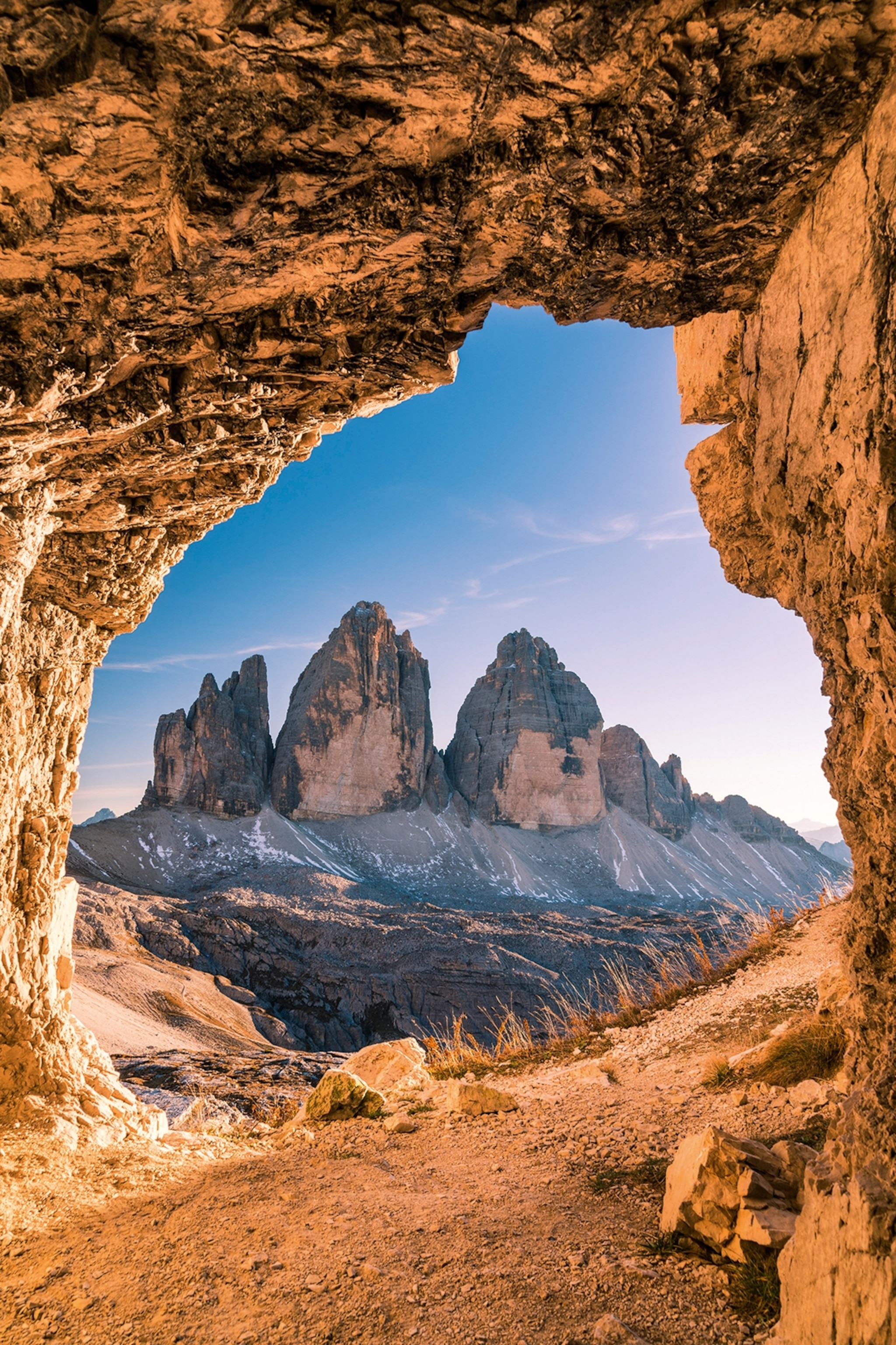 A view of the The Tre Cime di Lavaredo peaks in Italy captured through a natural formed rock archway.