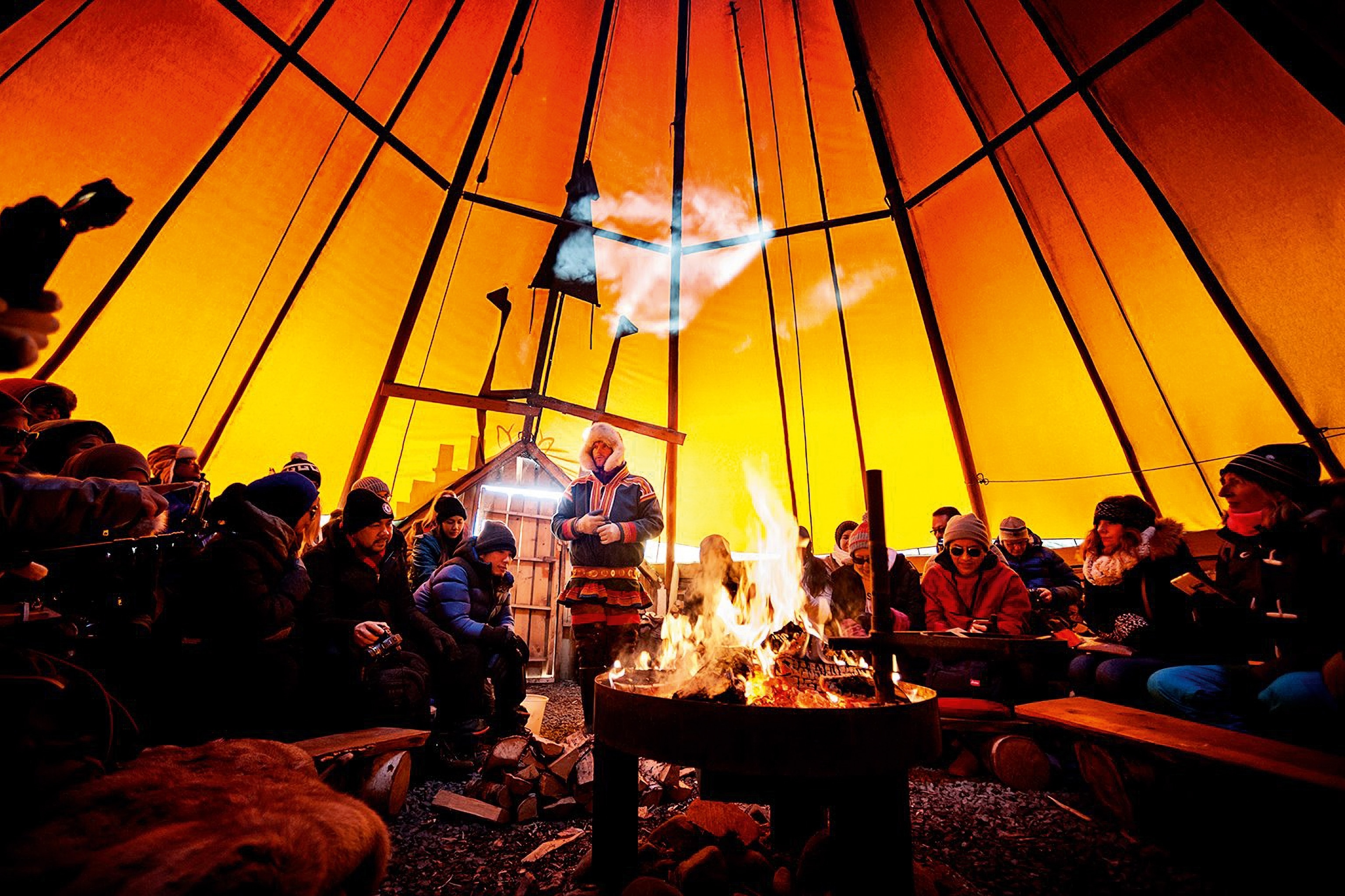 group of people inside a tent around a fire