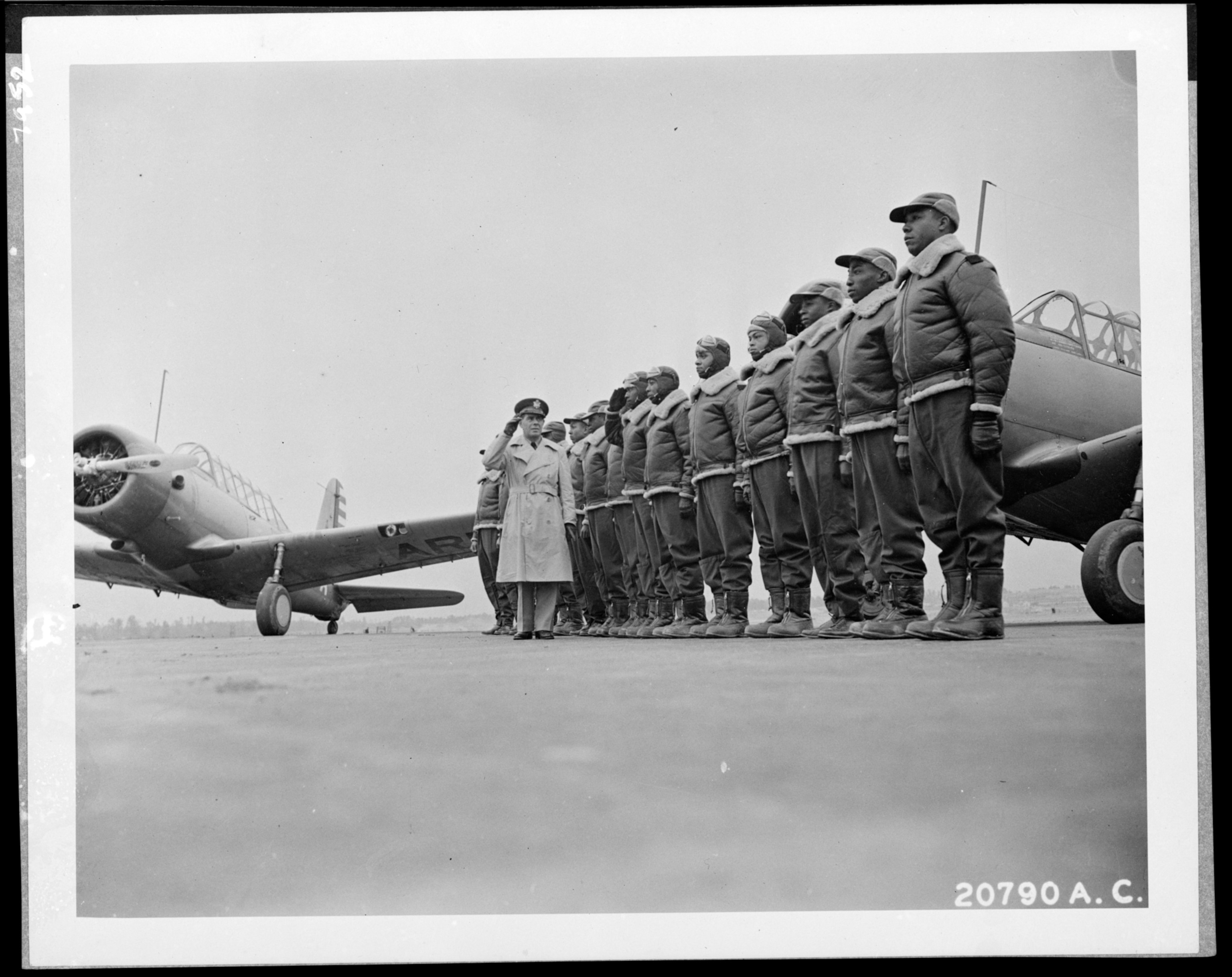 A group of soldiers lined up with a plane in the background