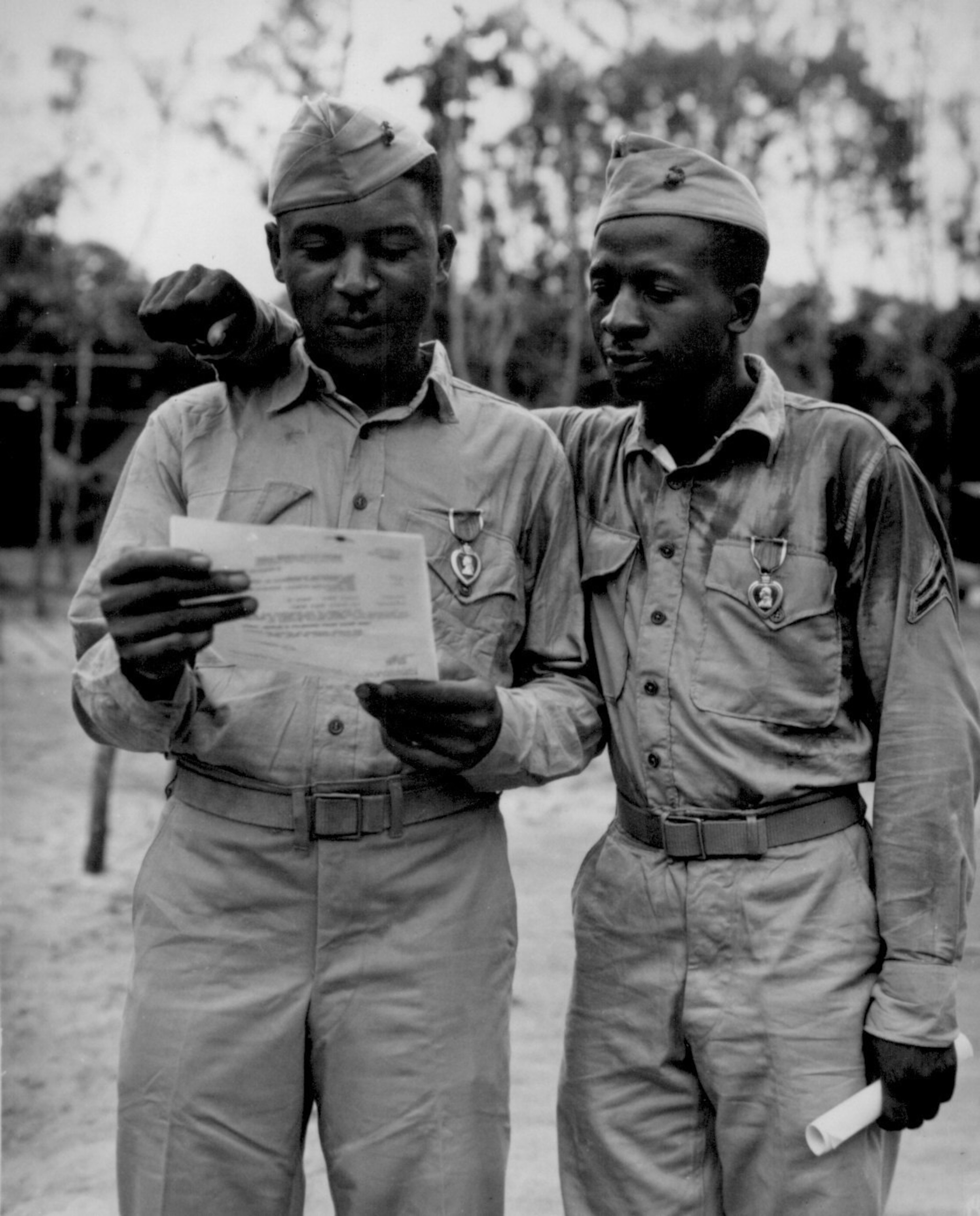 Two black Montford Point Mariners stand and read a letter.