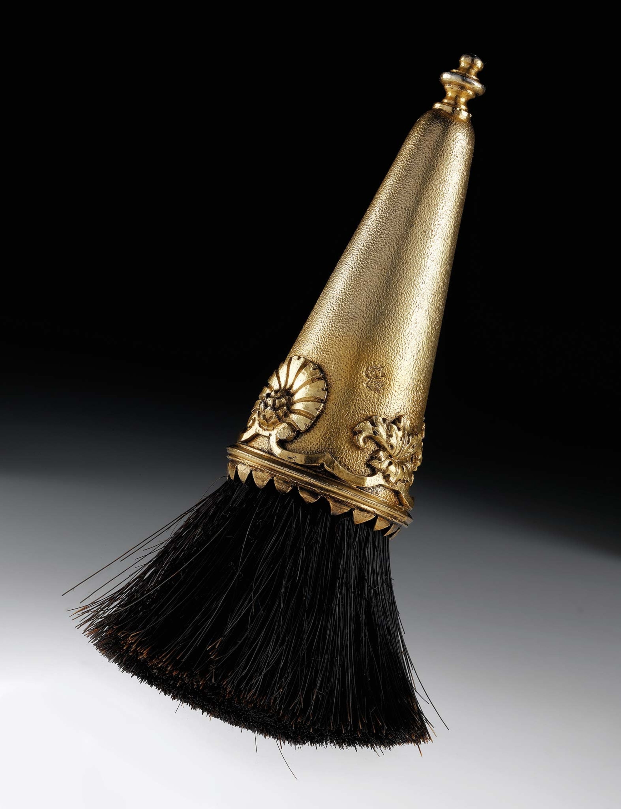 A makeup brush with a silver gilt handle