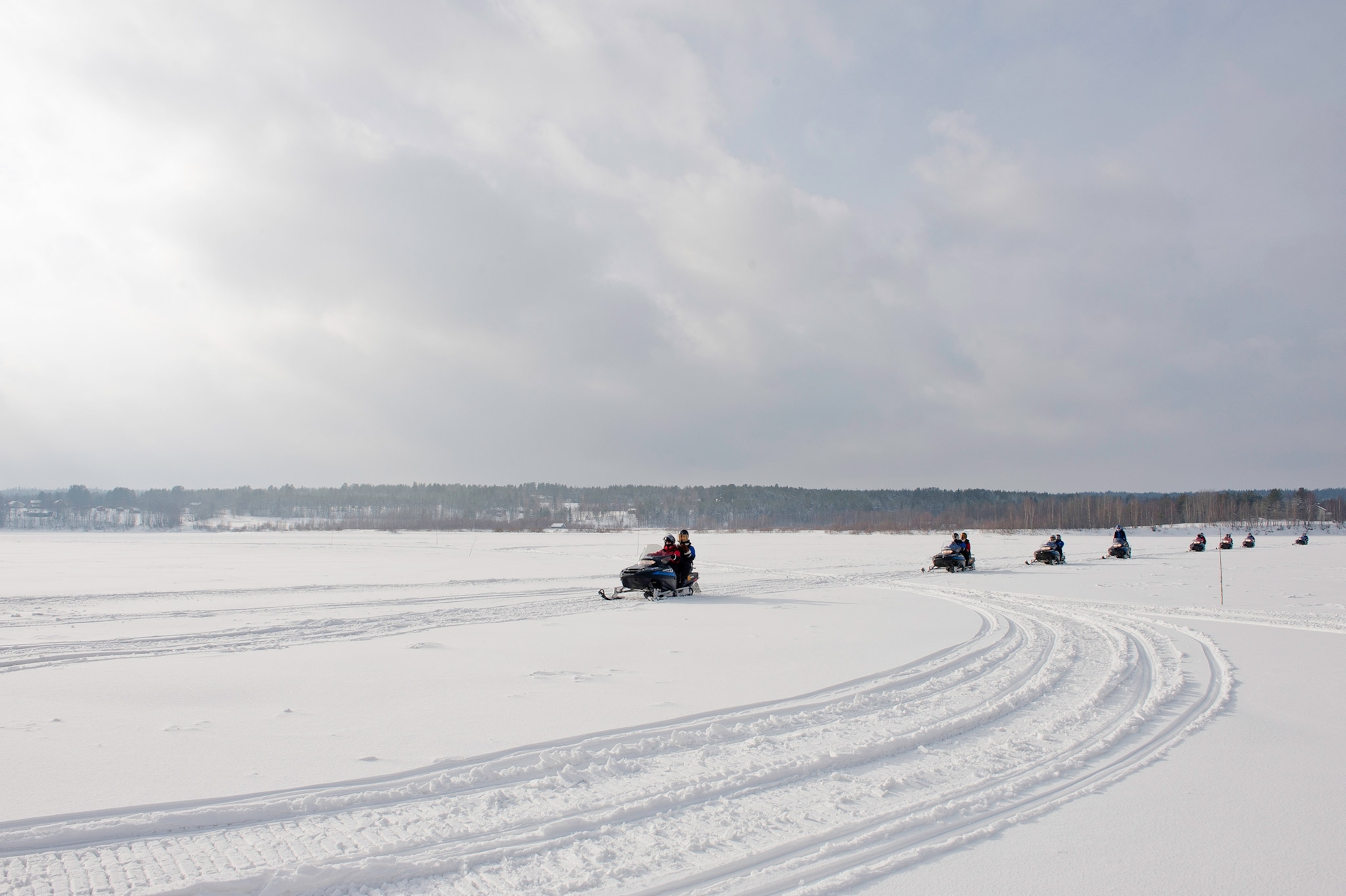 Clad in black snow-gear and sleds riders glide across the snow.