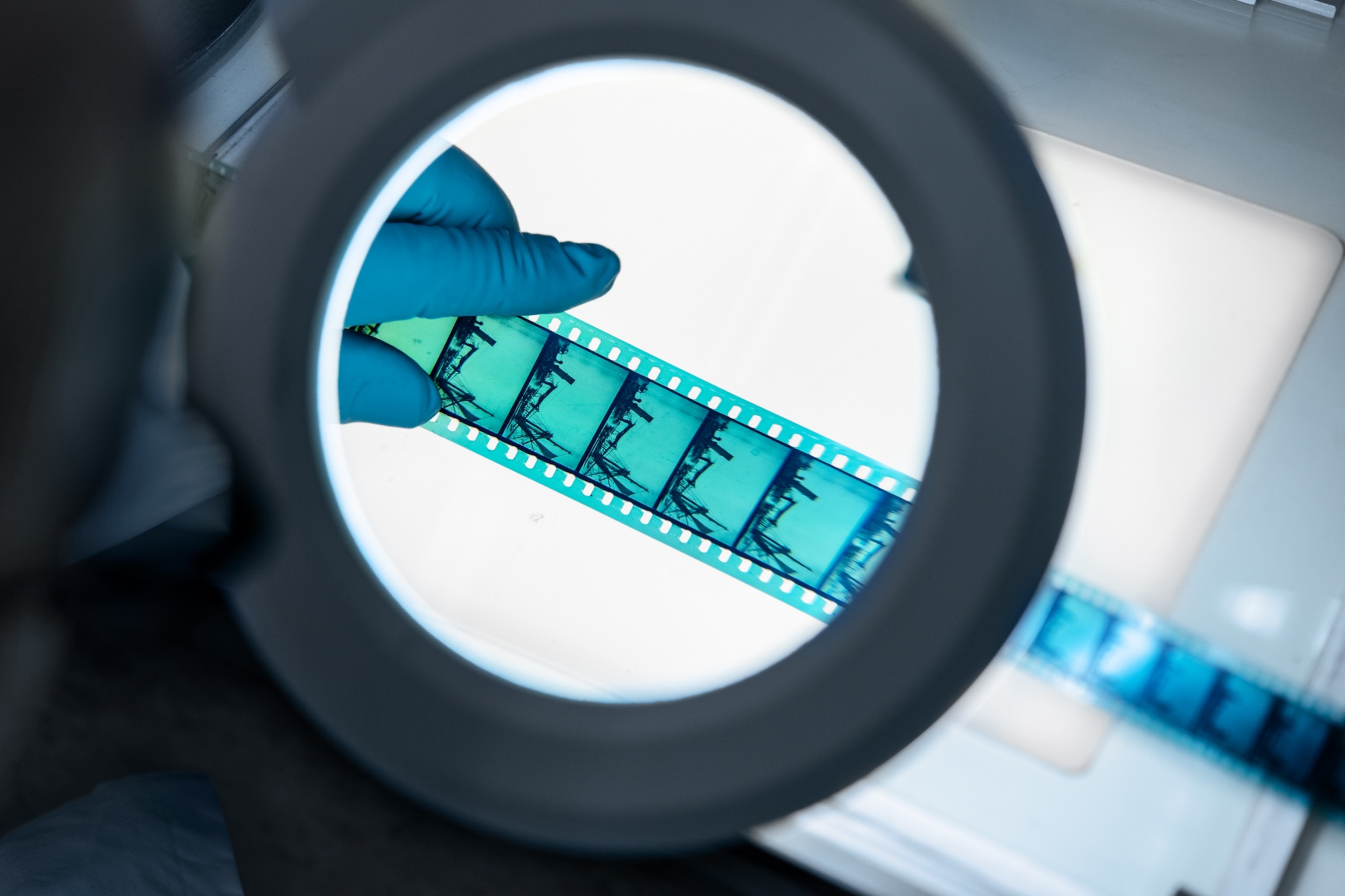 A magnifying glass examines blue nitrate motion picture negatives