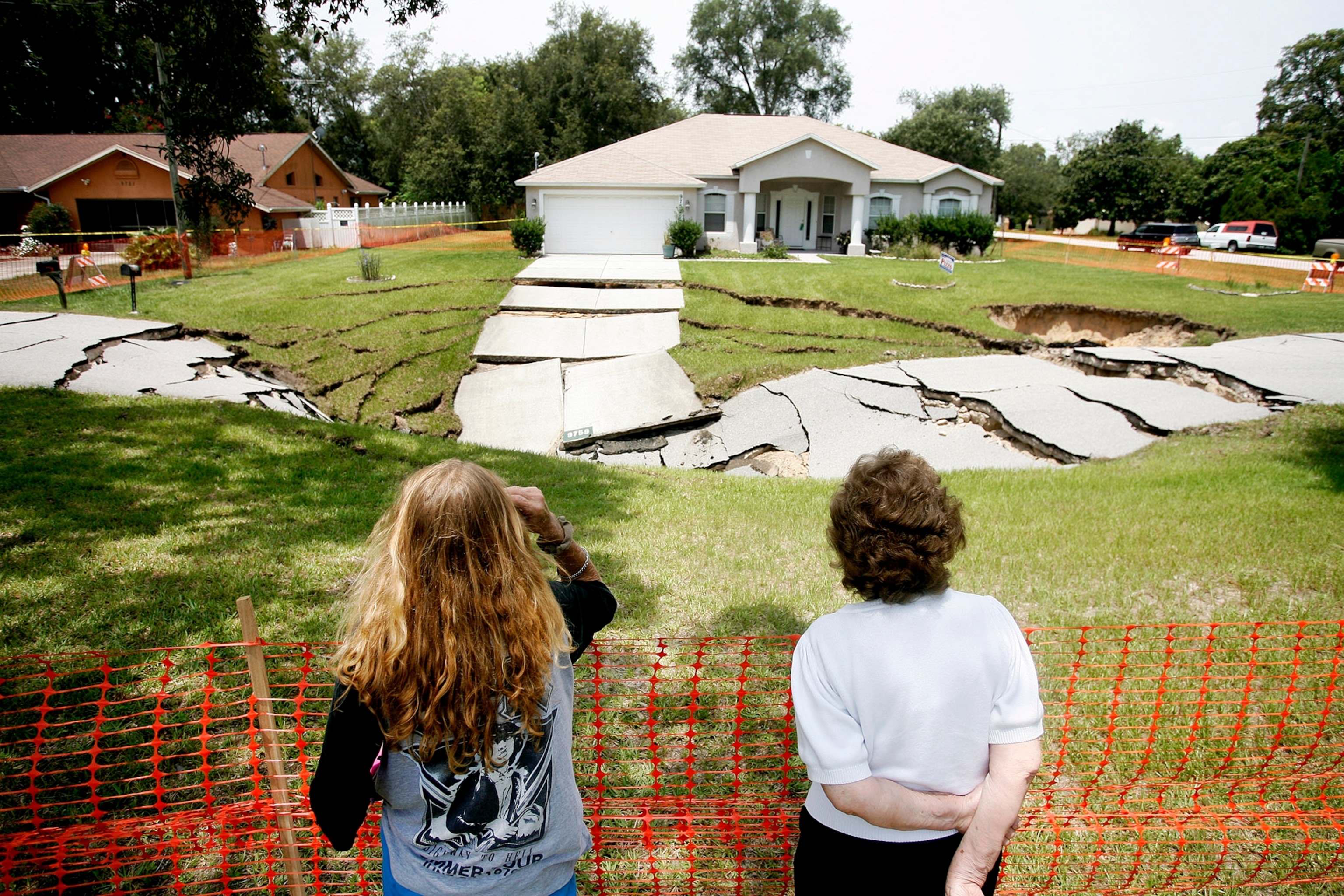 Kim Russell, left, who lives nearby on Gilbralter Street and her mother Betty Box both examine the massive sinkhole that opened on Eldridge Road in Spring Hill, Fla., Saturday. T