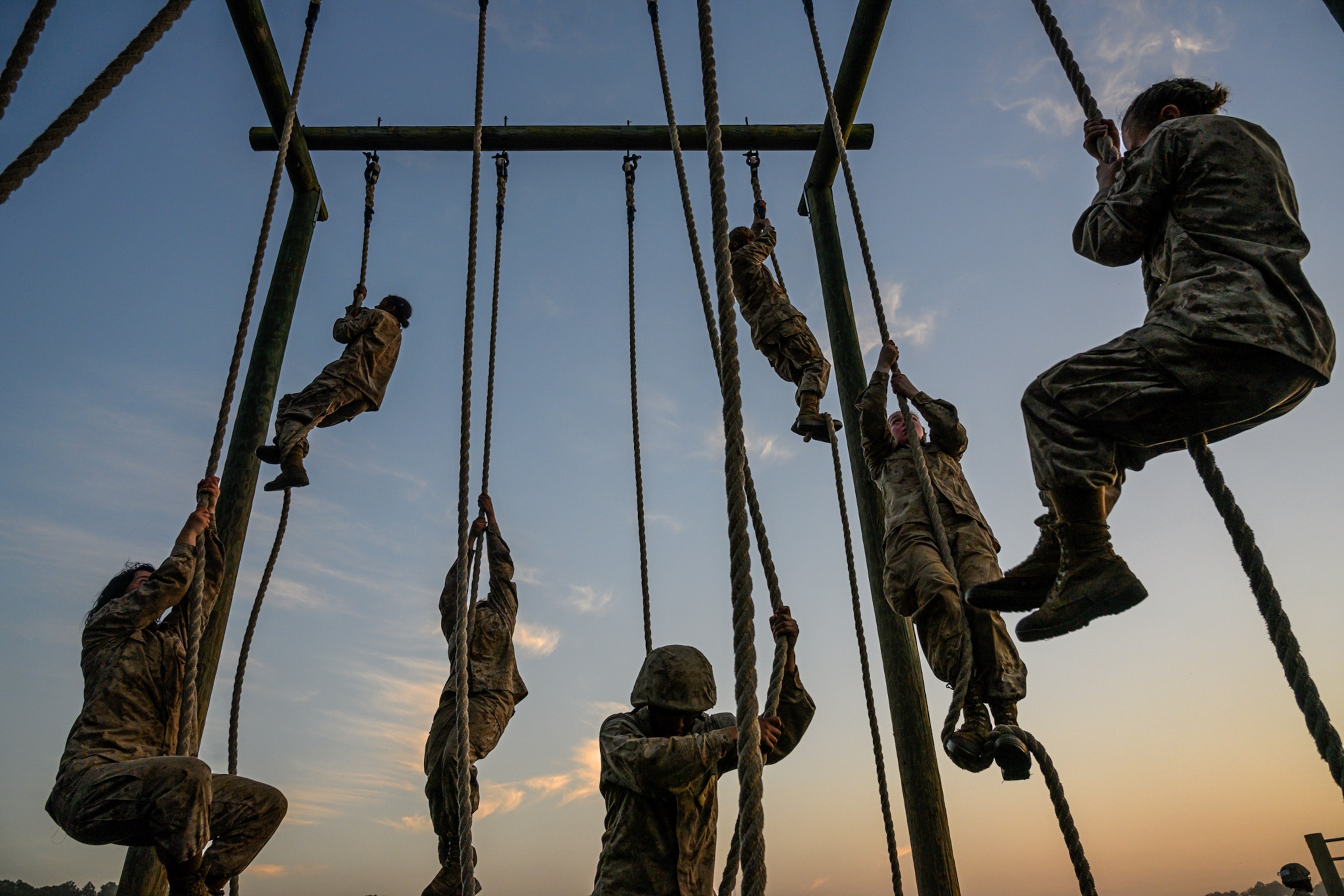 seven people climbing up ropes at sunrise