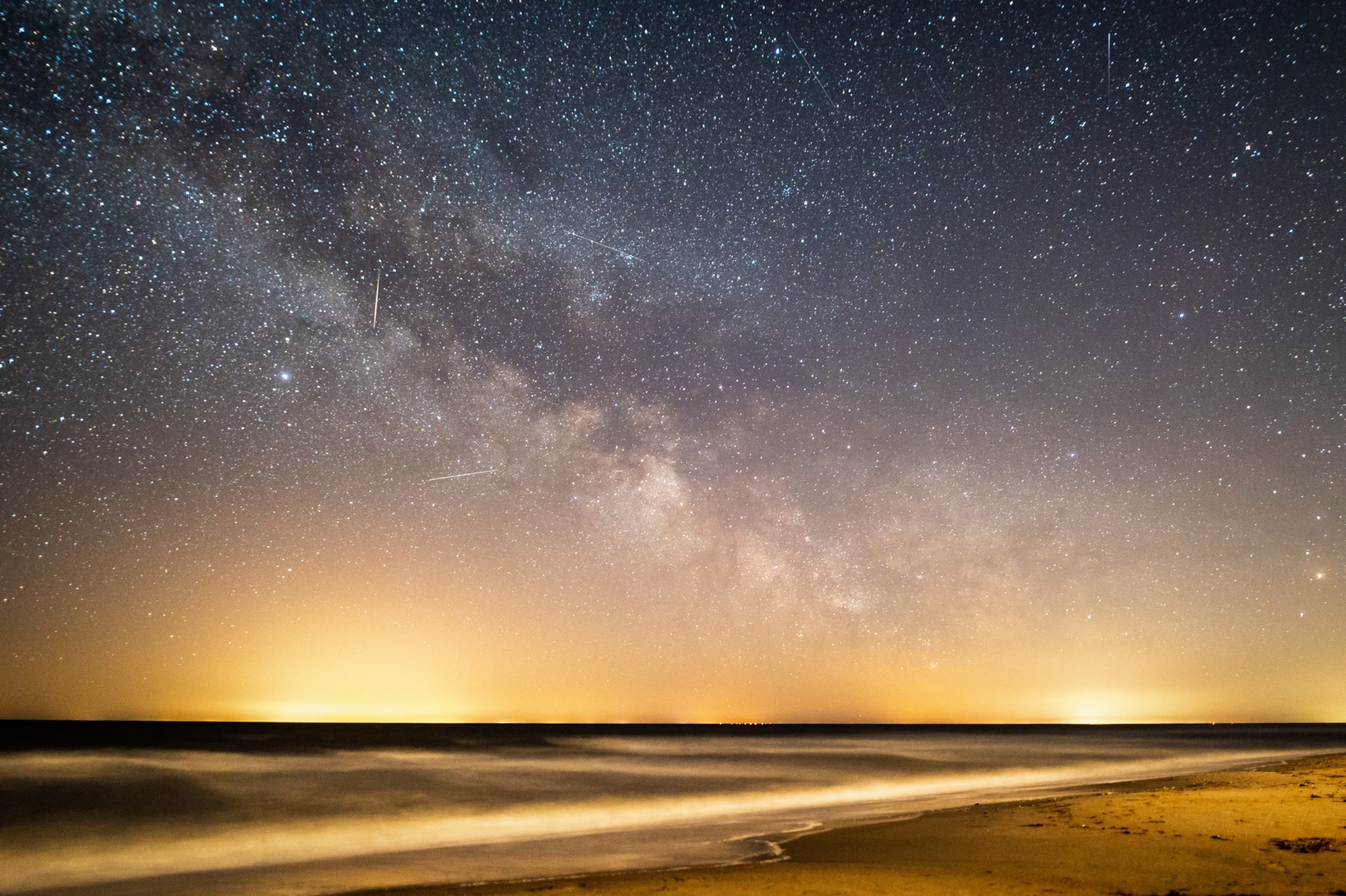 Shooting stars are visible amongst a clear view of the Milky Way over thee Baltic Sea.
