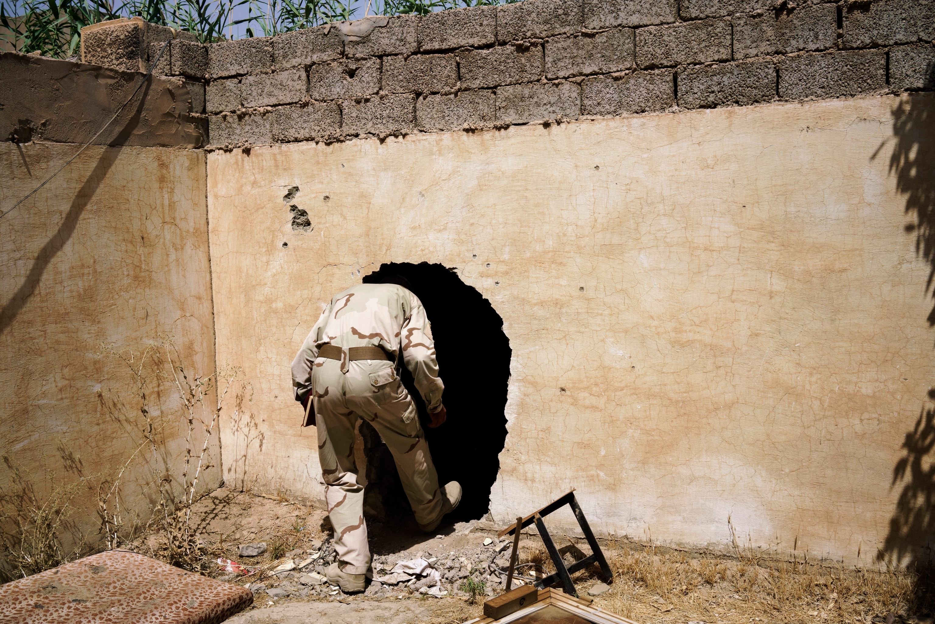 an Iraqi solider walking into a hole connecting two buildings