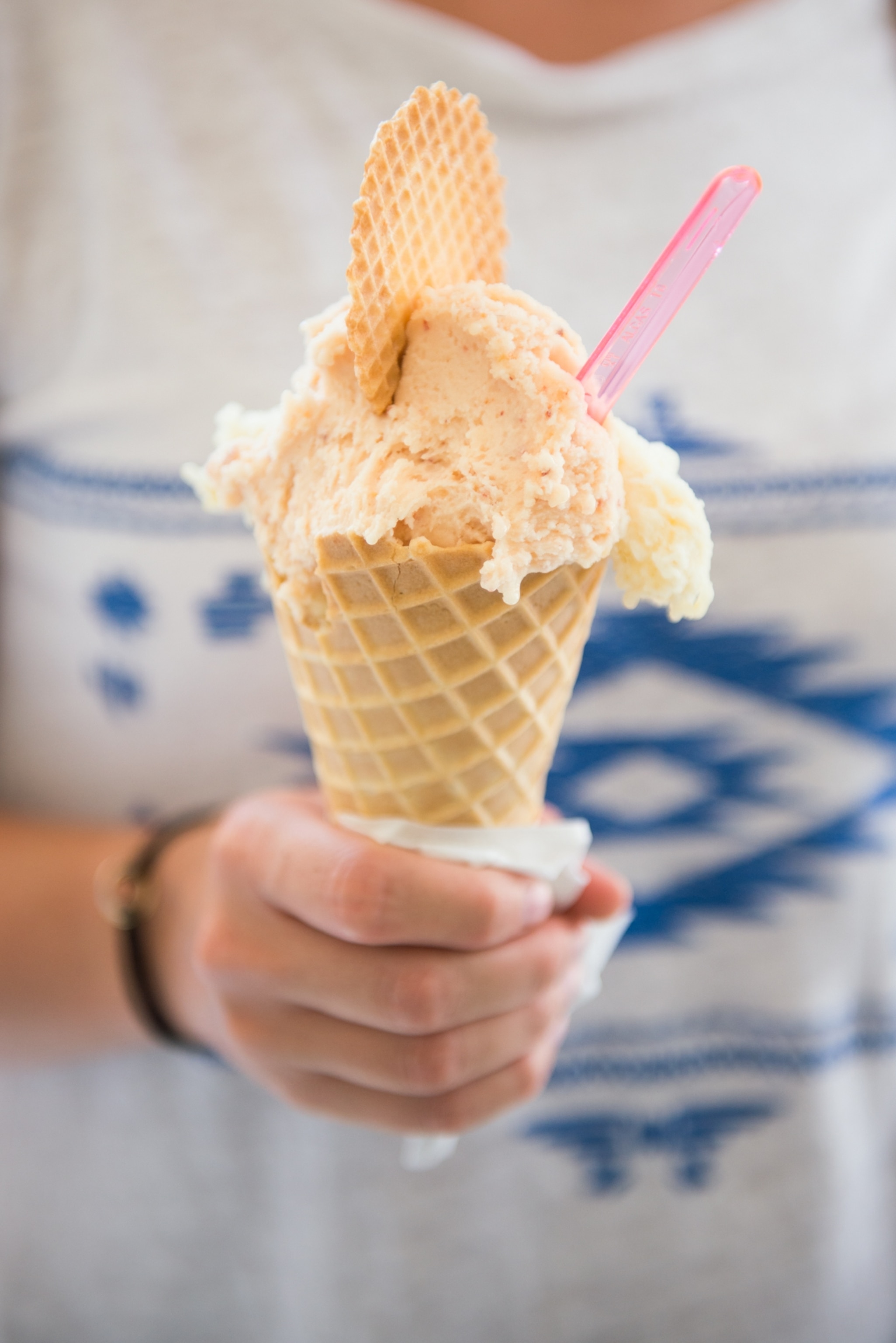 A woman holds an ice cream waffle cone.