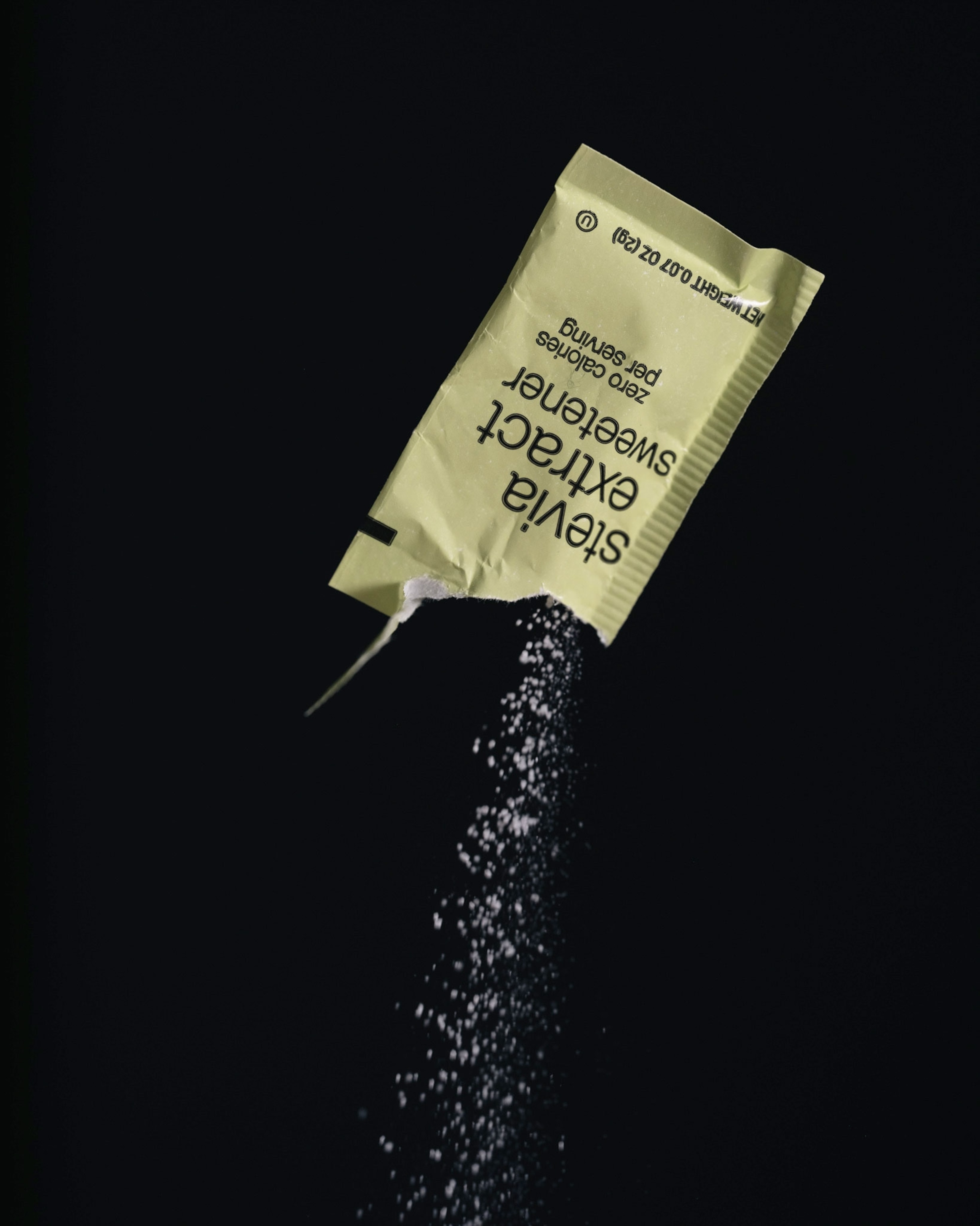 Studio shoot with black backdrop showing packets of artificial sweeteners