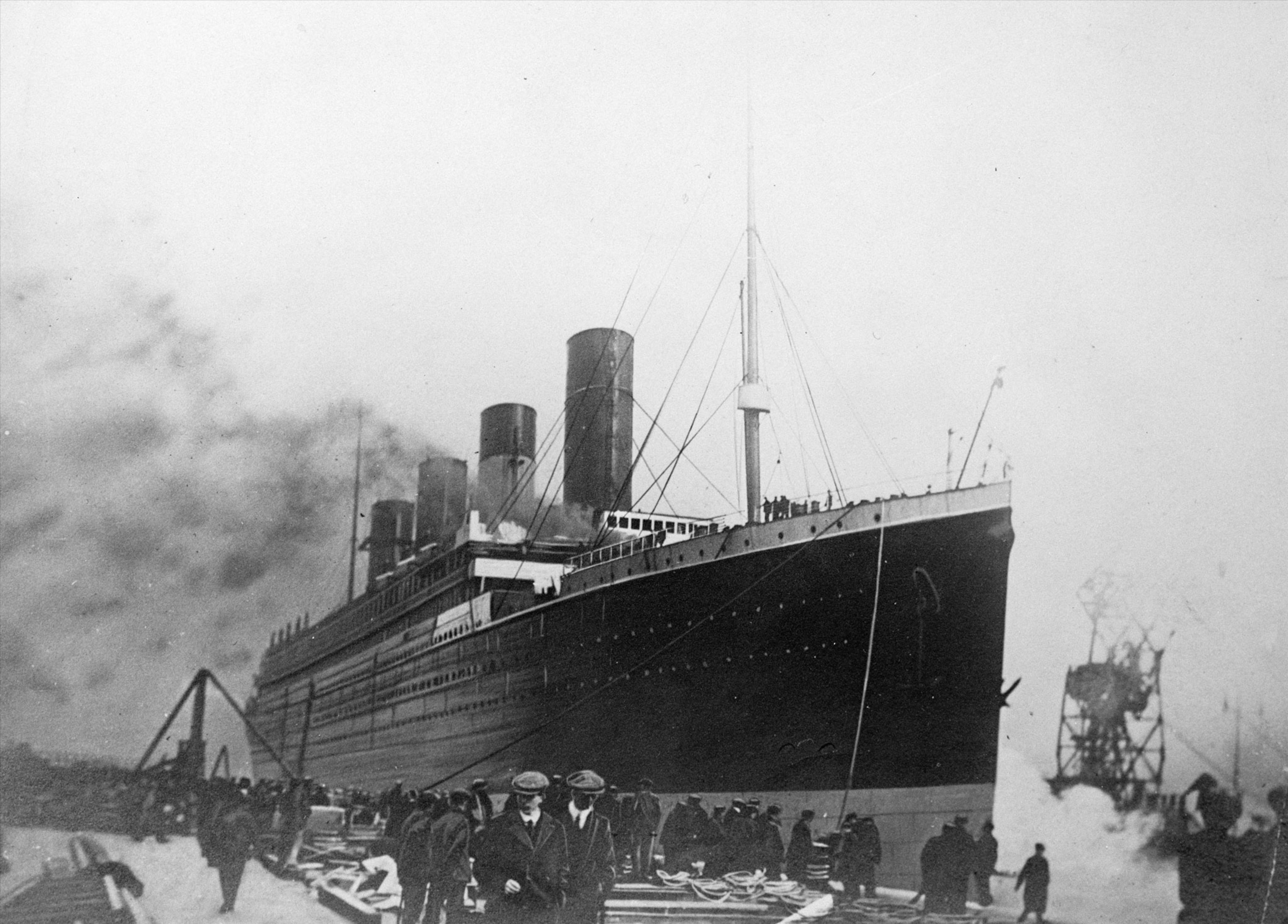 the giant ship titanic near a dock with smoke billowing