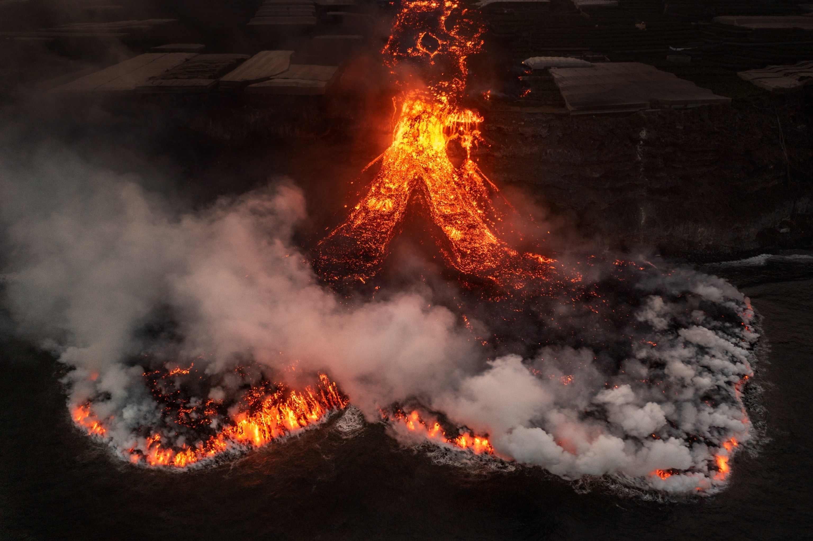 Picture of aerial view of mount and two lava stream pouring from it.