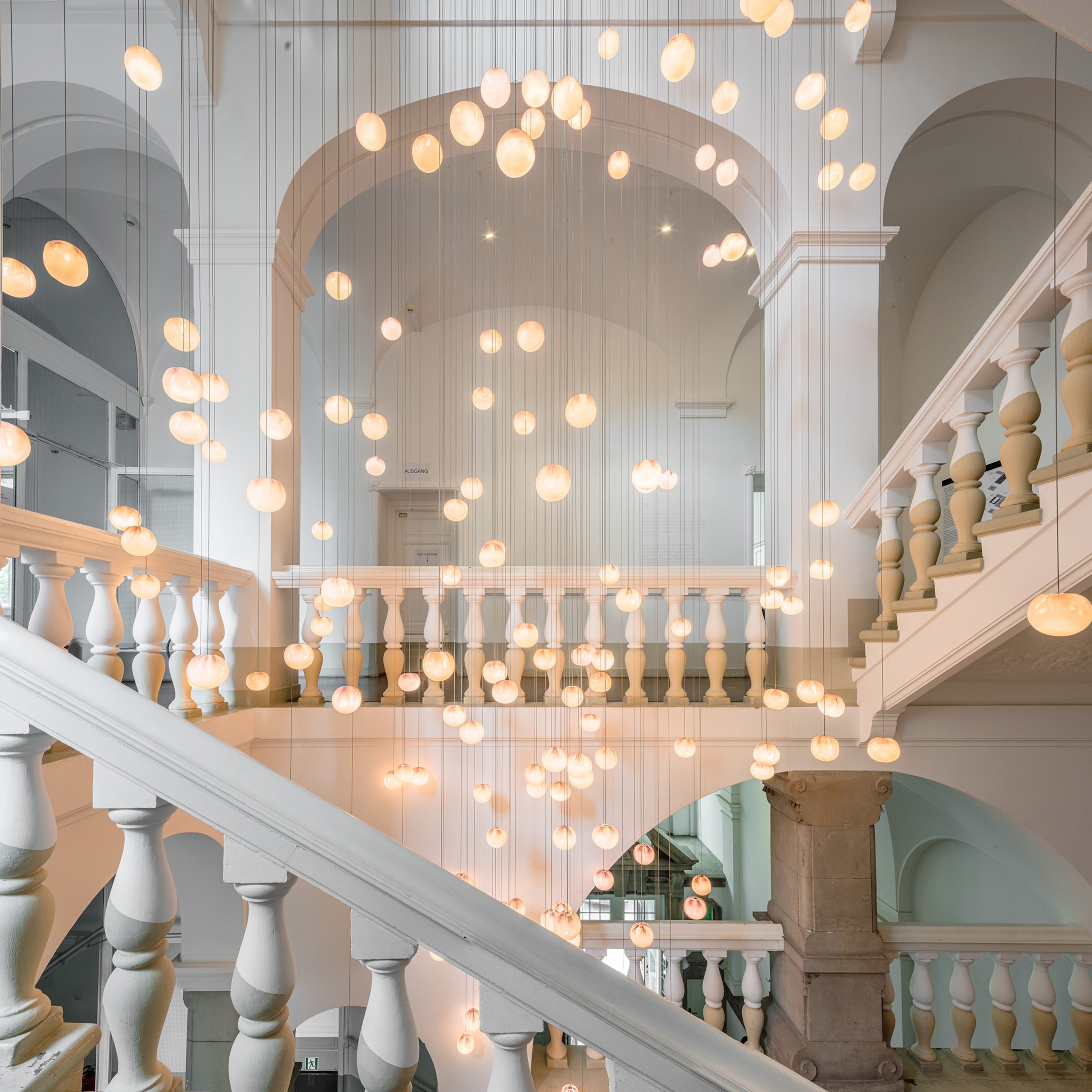 A light installation hangs in the modern, white-painted stairwell of the Wilmina Hotel.