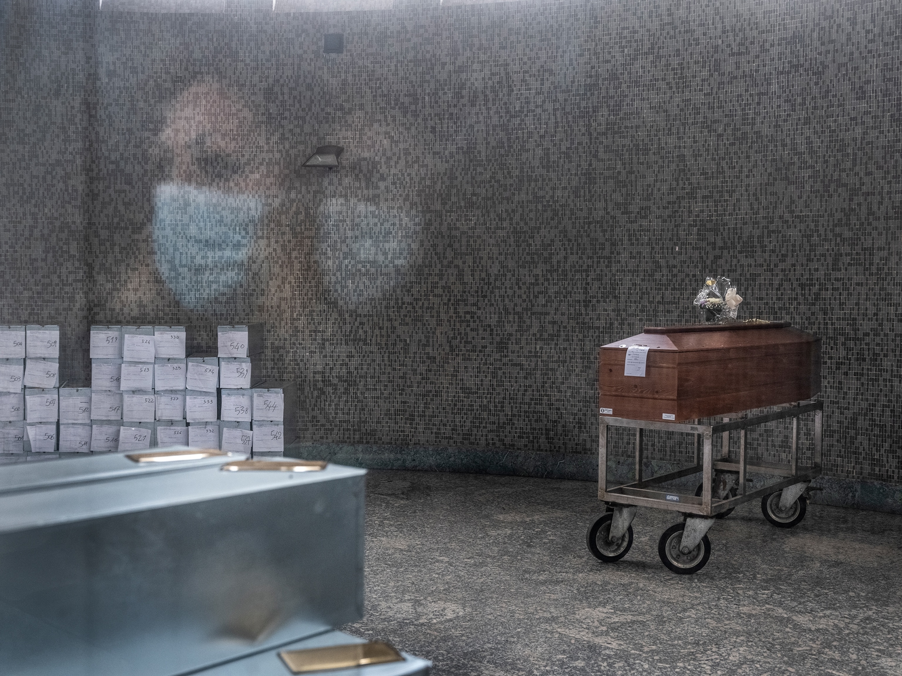 a woman looking at a coffin behind class in the mortuary