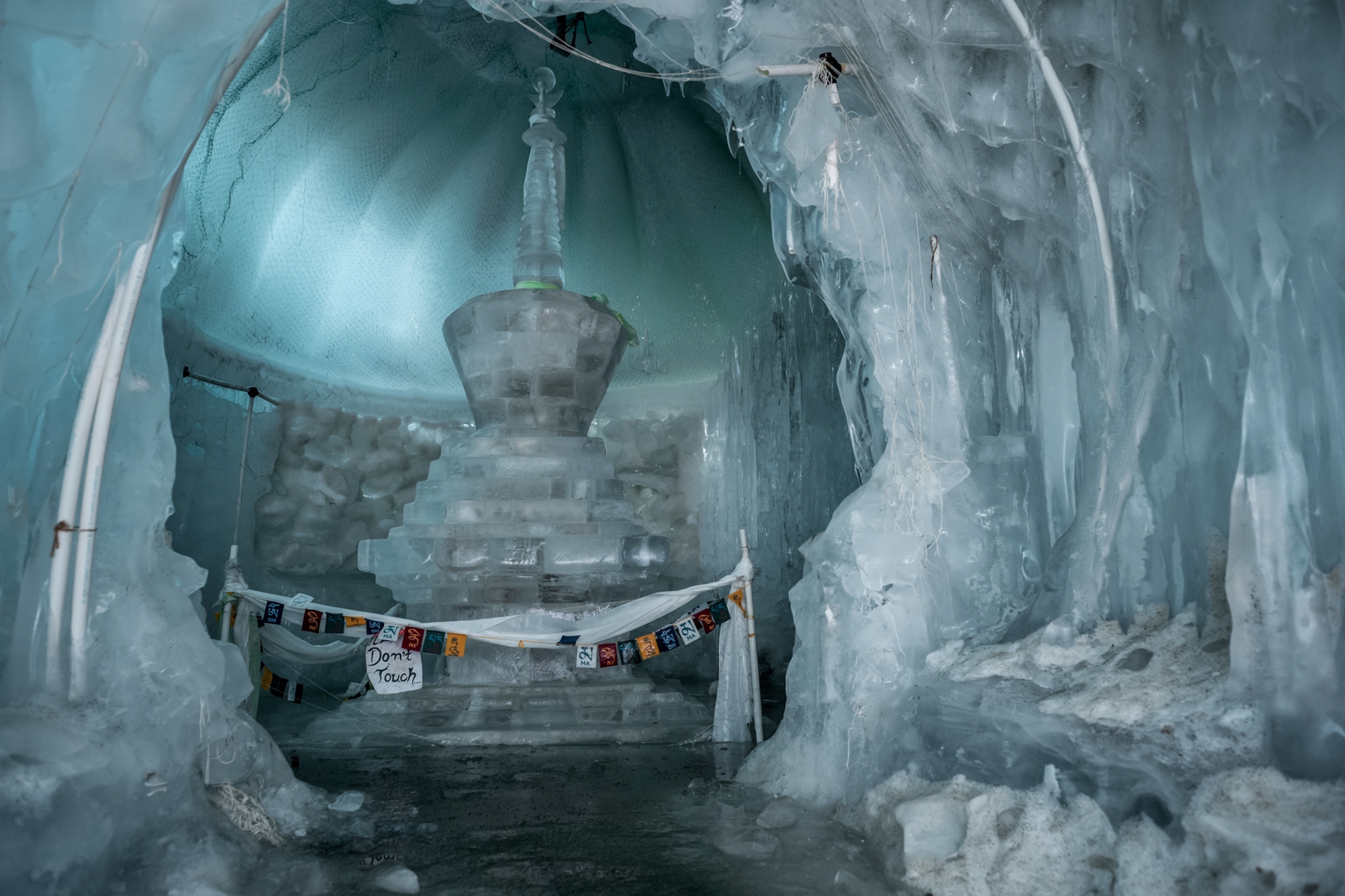 inside of ice cave with relics and Buddhist flags.