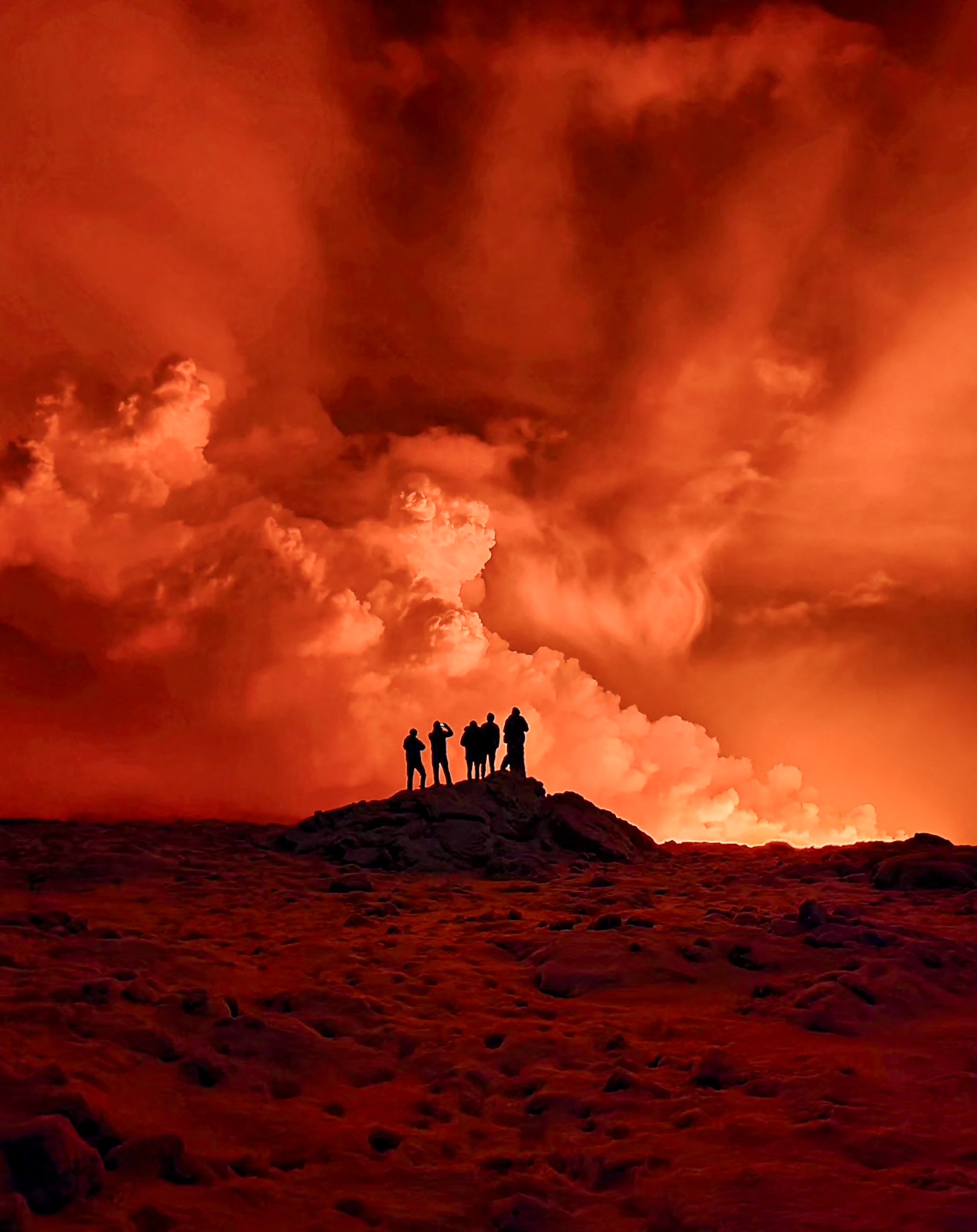 A group of people are silhouetted against a dramatic orange sky.