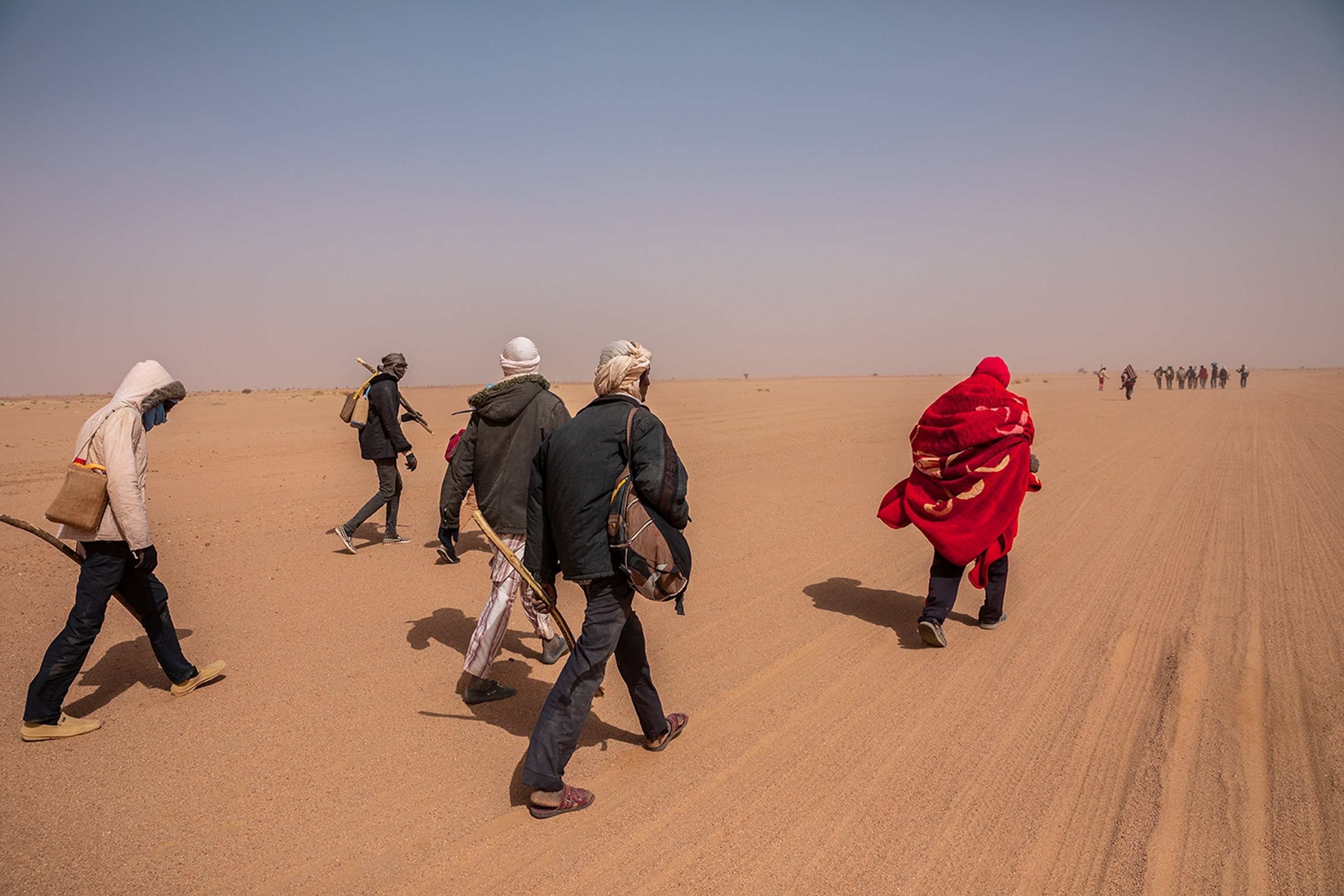 men wearing protective clothing walking through a desert