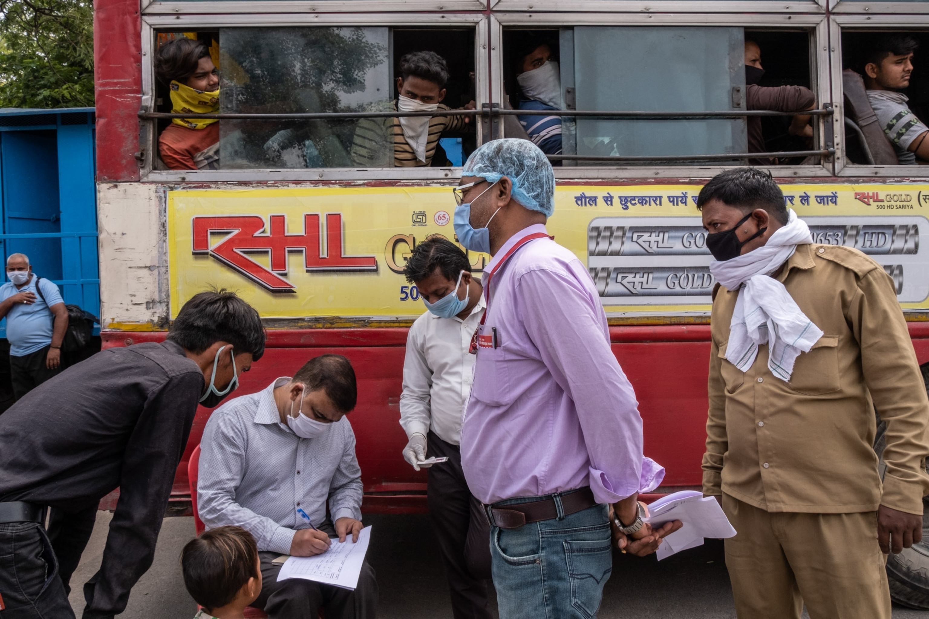 a few people standing outside of a bus, some people in the bus window
