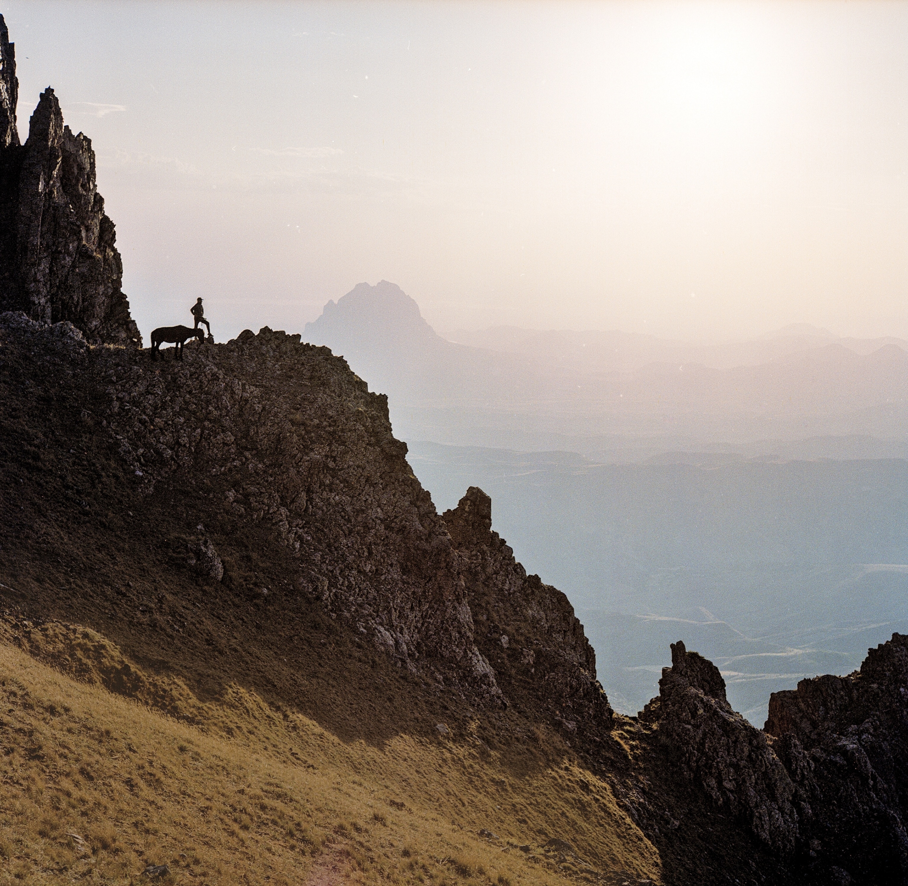 A man standing on a mountain ridge surveying the view.