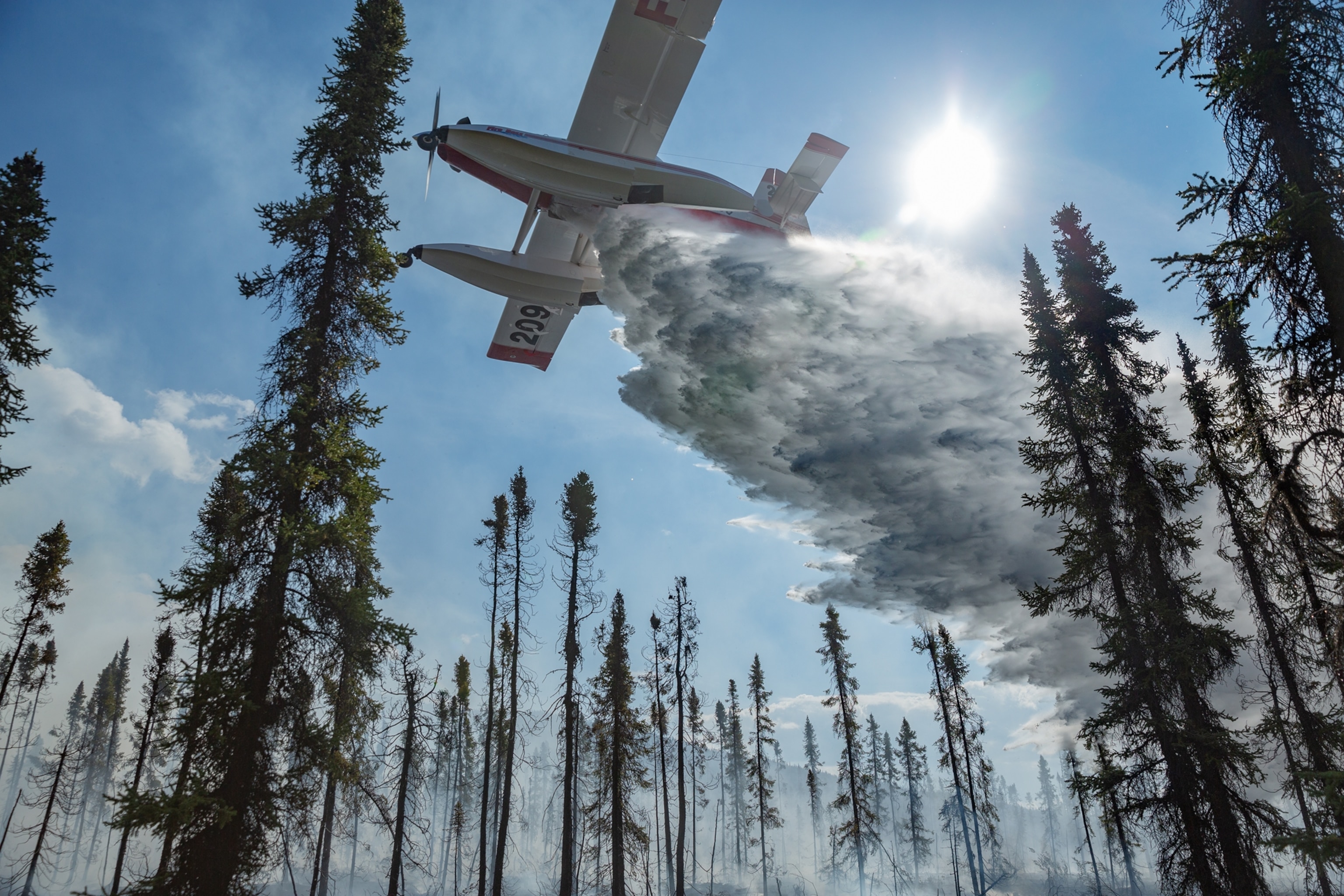 a plane in blue sunny sky dumping water