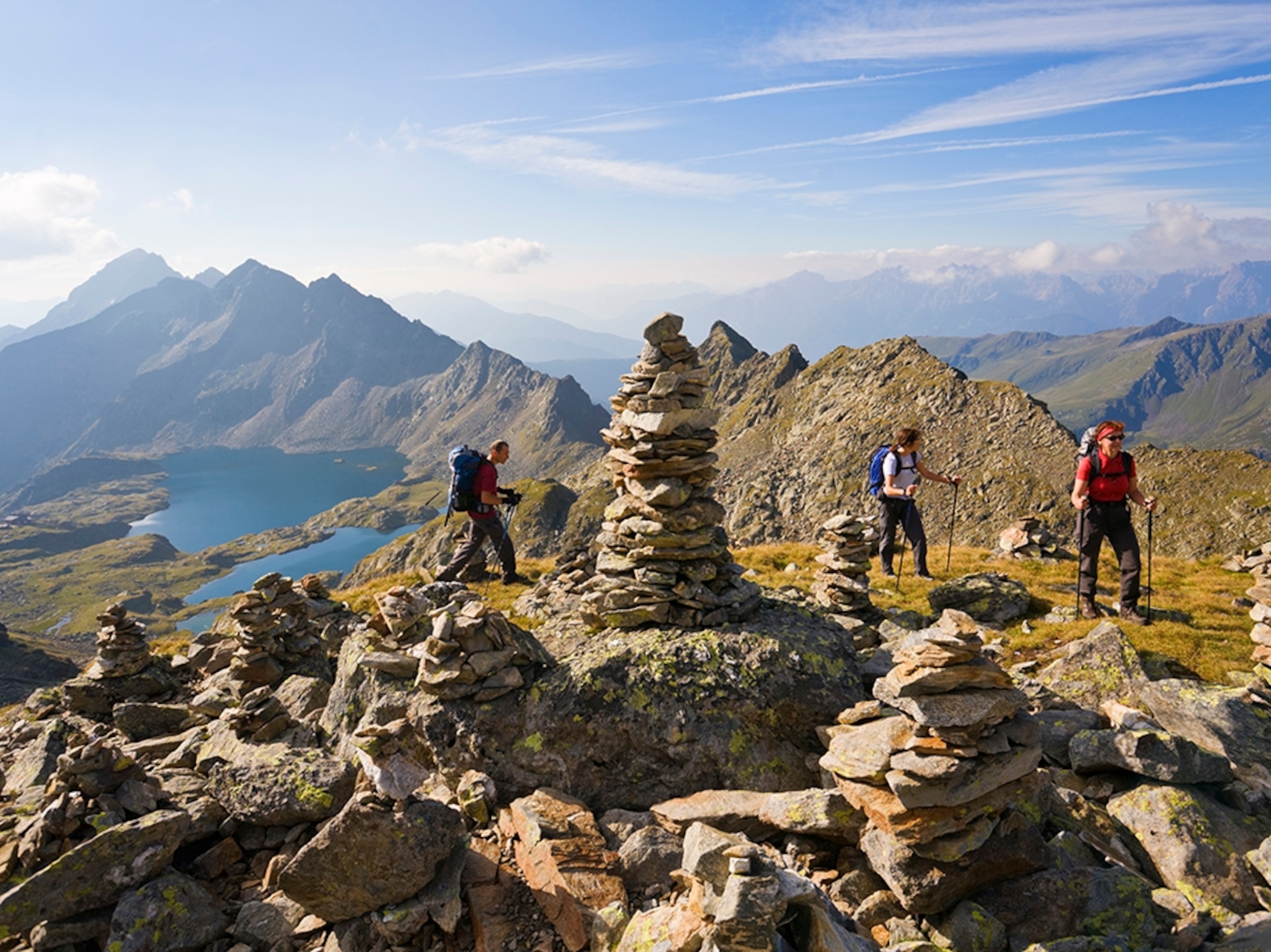 a group of hikers walking near a set of rock cairns in Schobergruppe, Austria