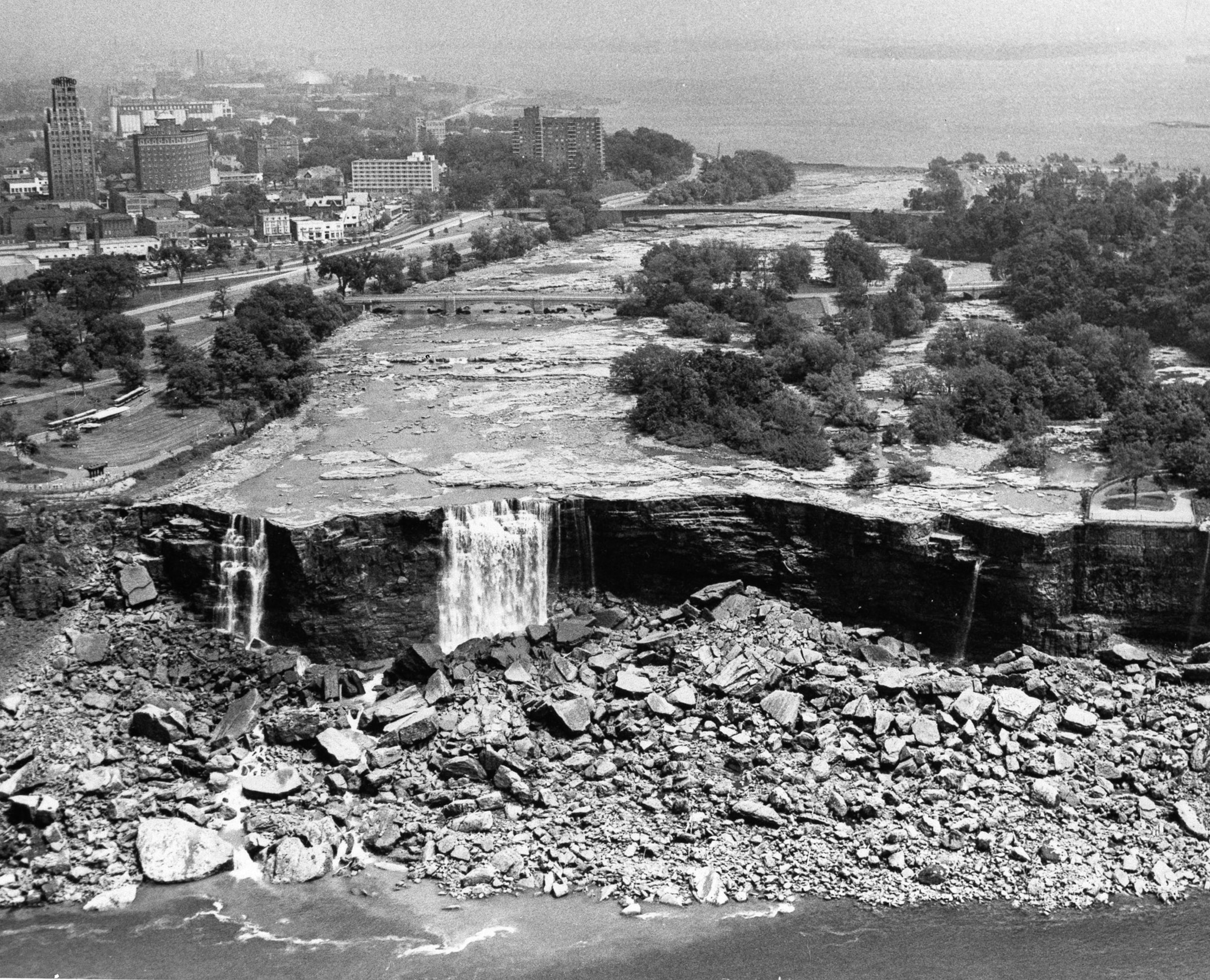 A Black and white image of the Niagara falls bits of broken rocks can be seen.