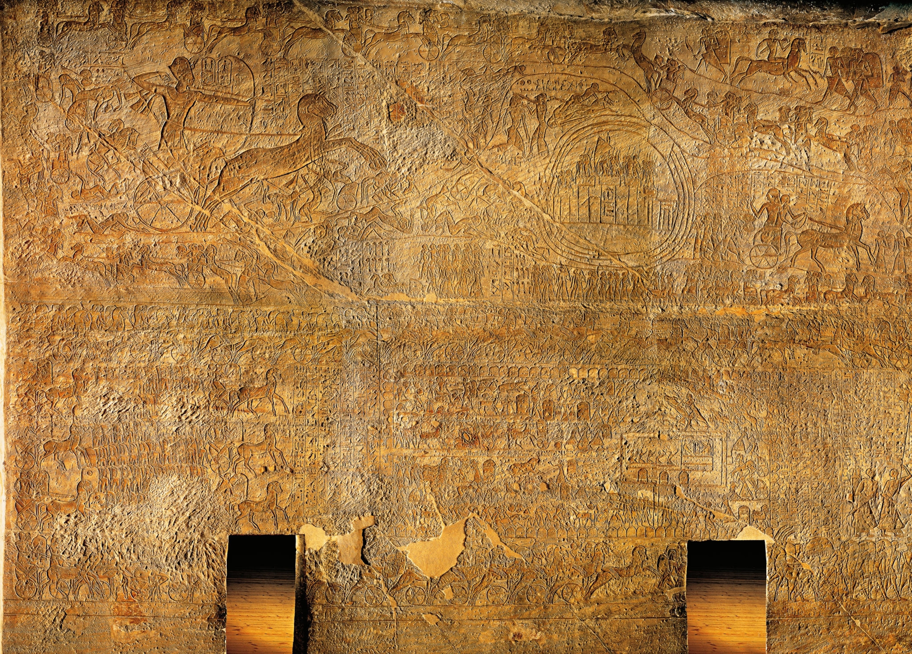 a stone relief of many chariots attacking