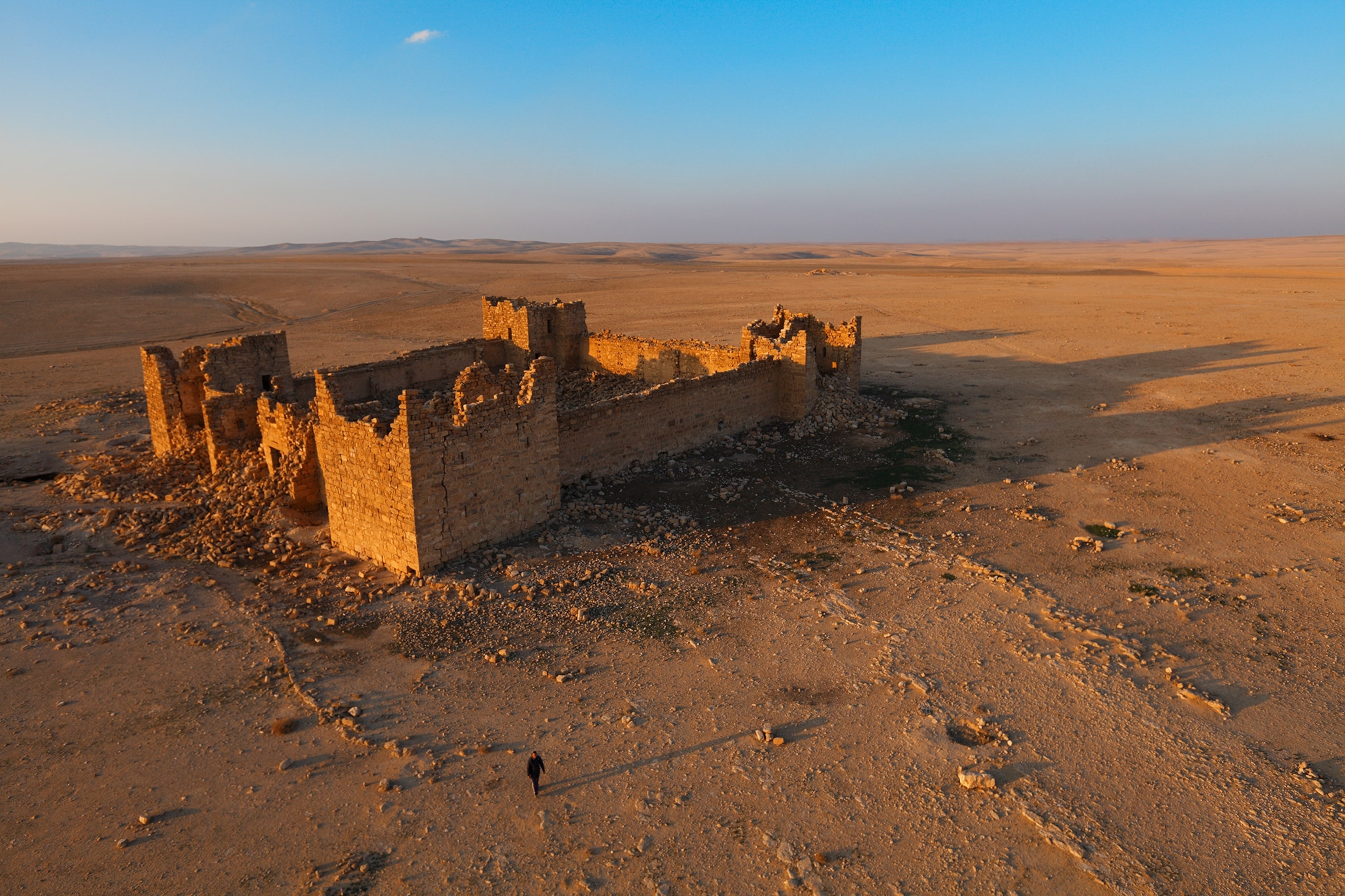 Deep blue sky and warm sun cascade on the ruins of a roman fort, debris sits around the remains from the aerial photo.