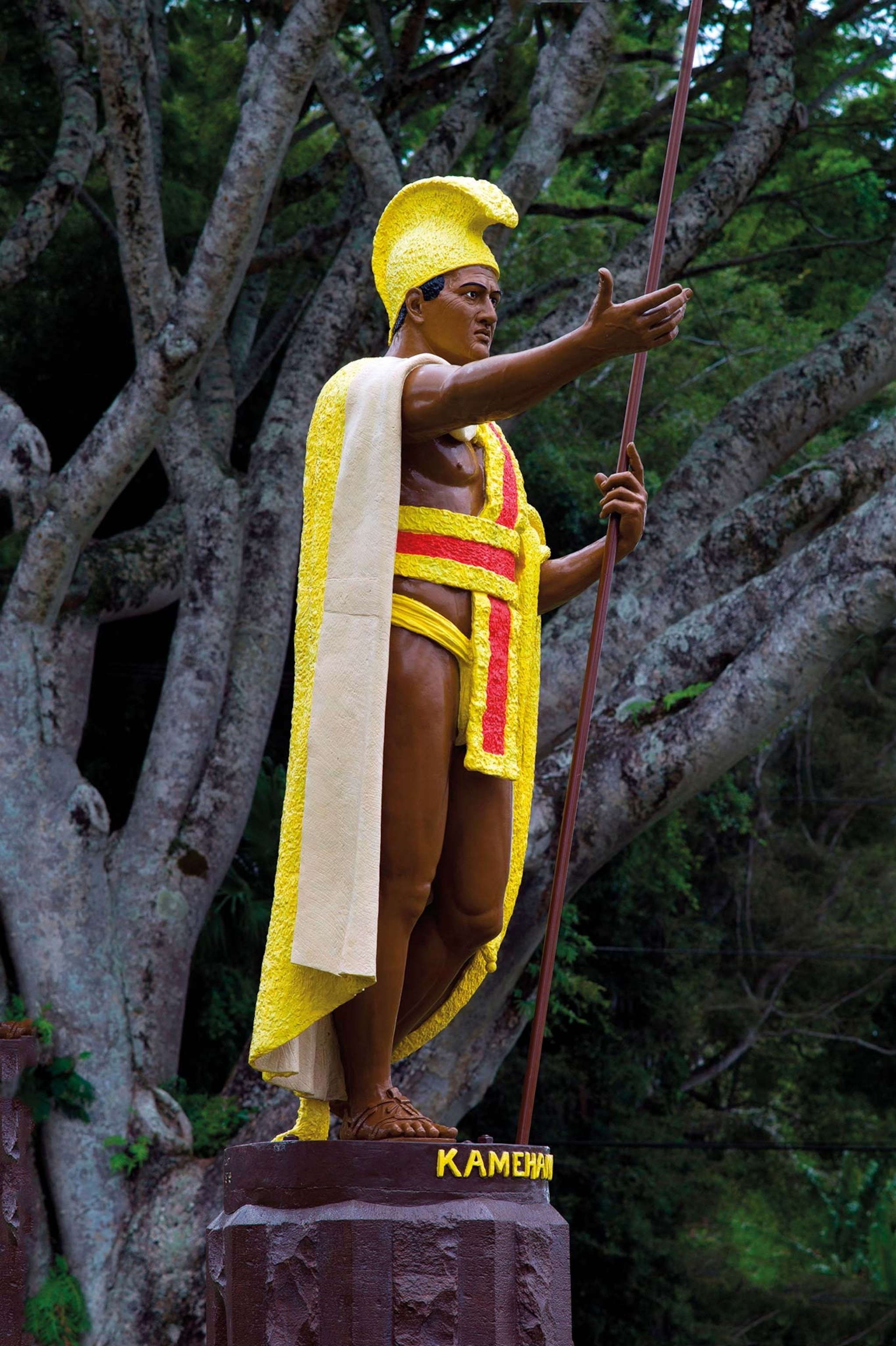 A statue of King Kamehameha with his arm out, wearing yellow and red regalia