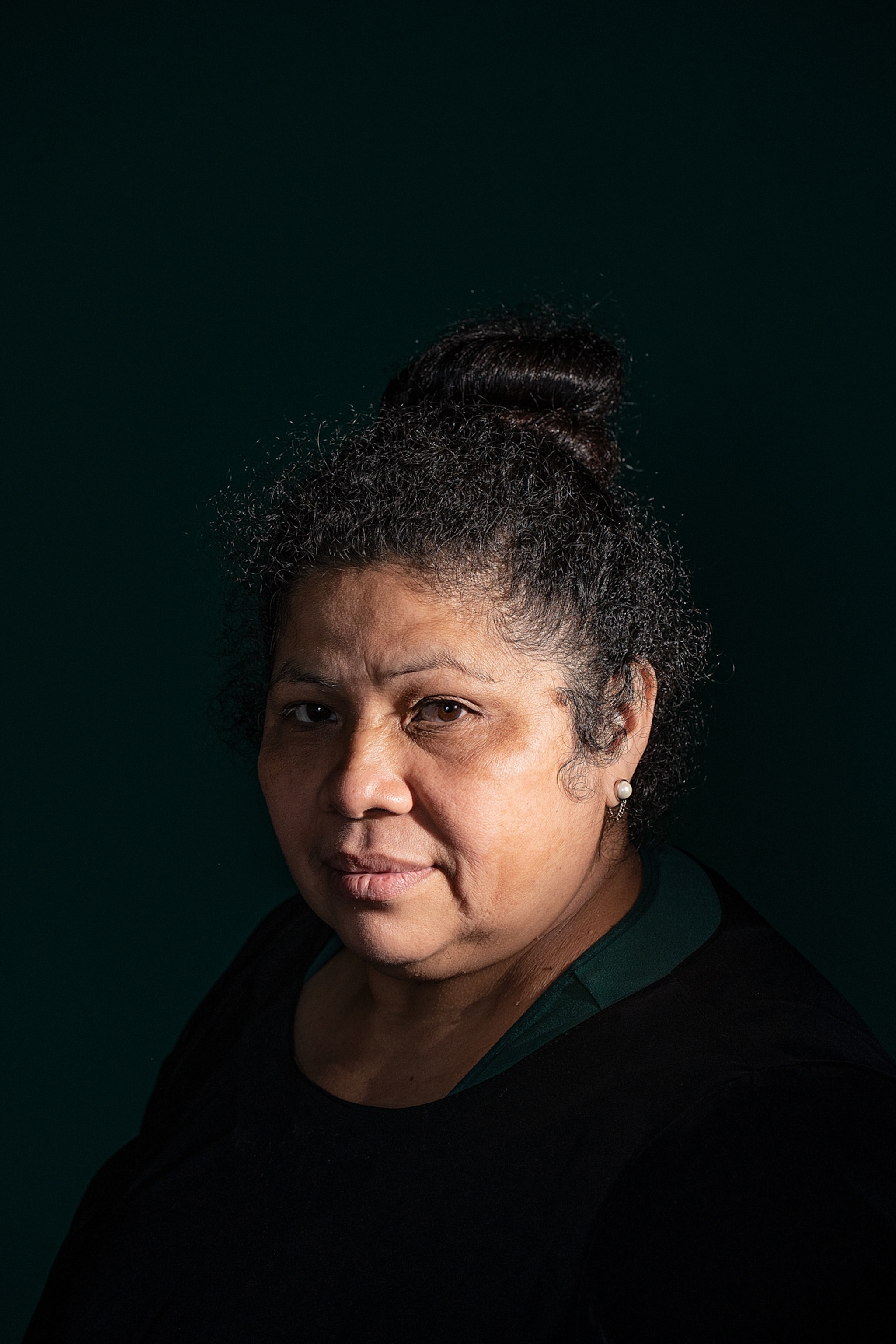 a woman against a black backdrop dimly lit