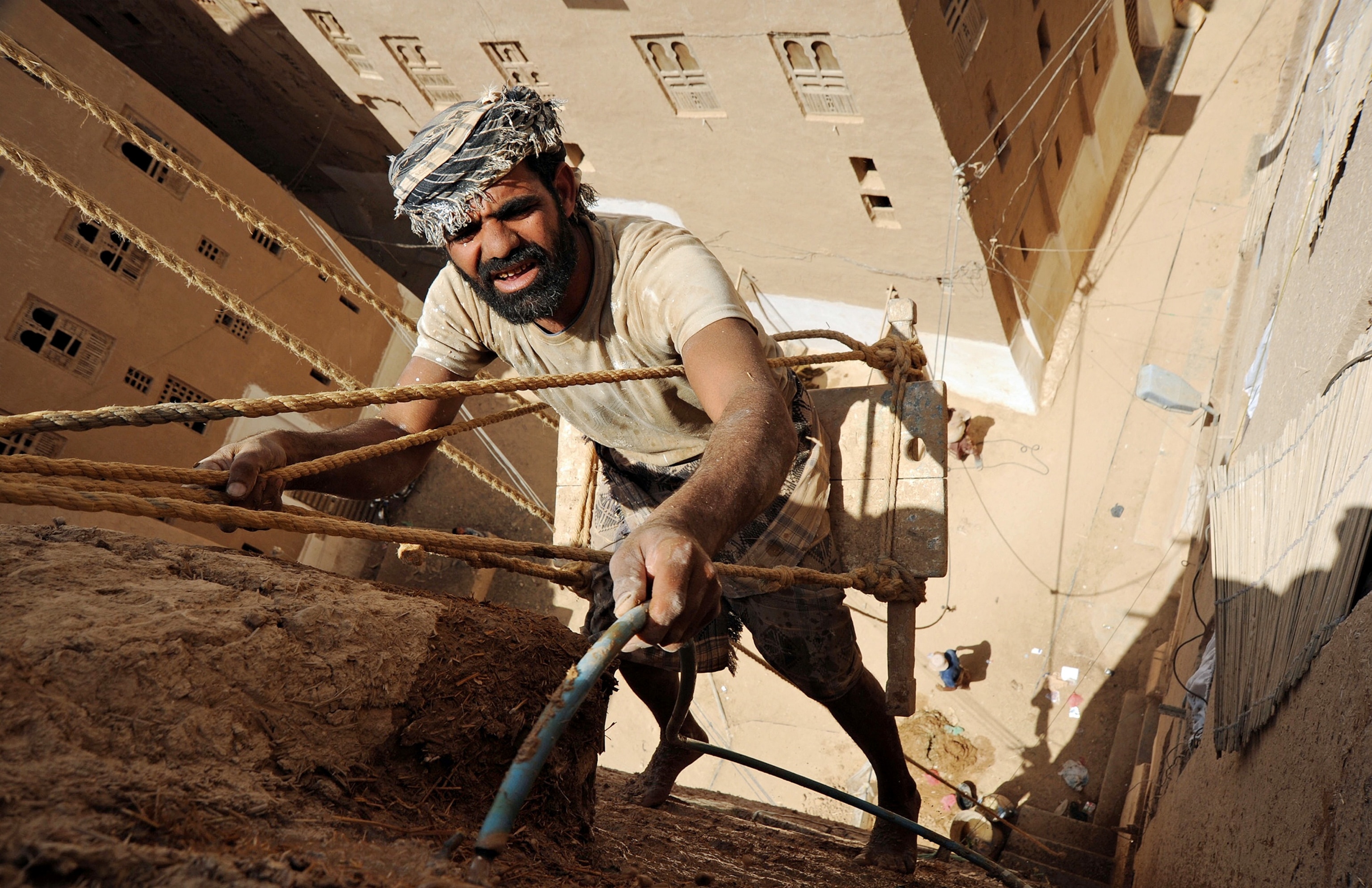 man repairing a mud building in Shibam, Yemen