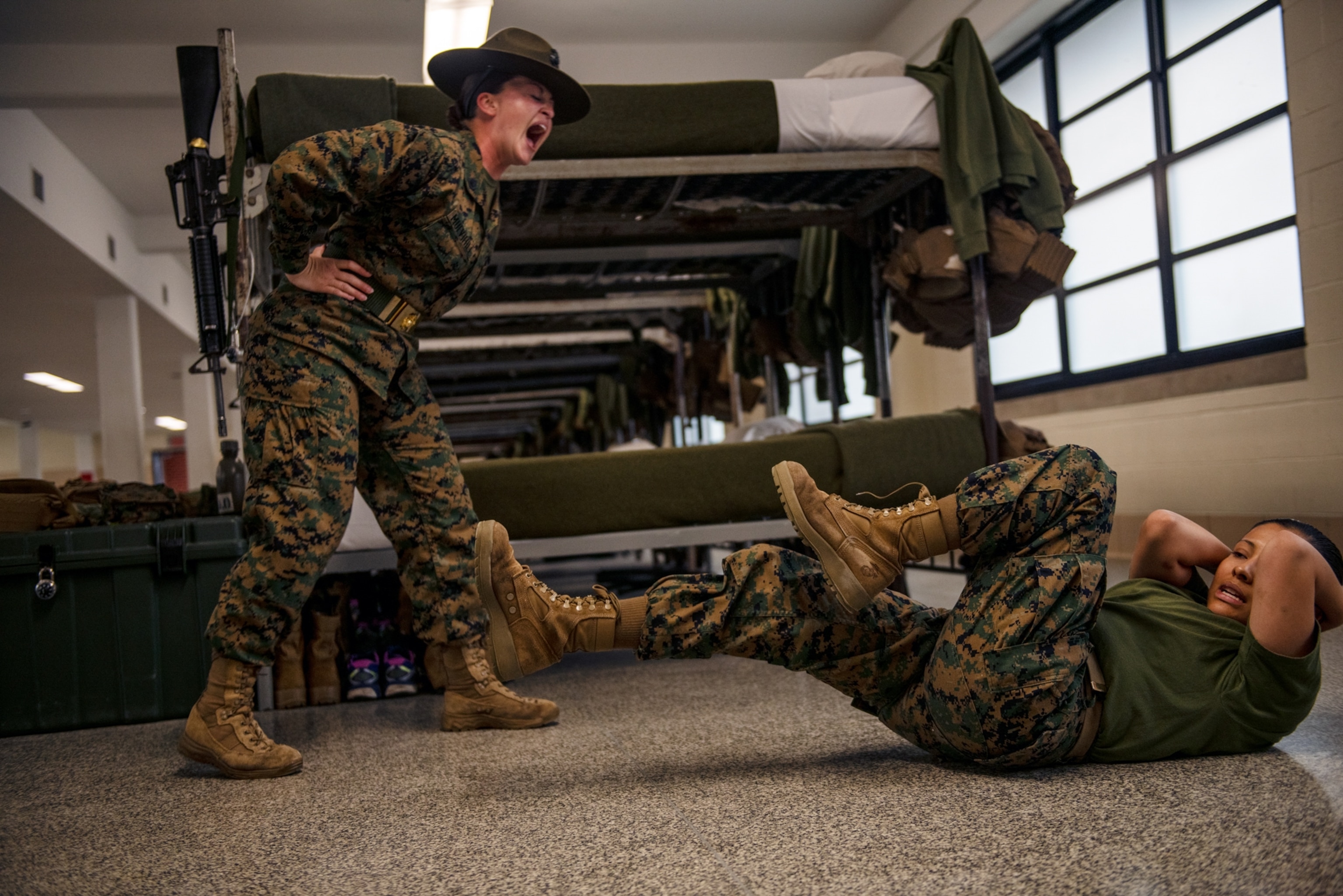 a sergeant yelling at a recruit as she does crunches