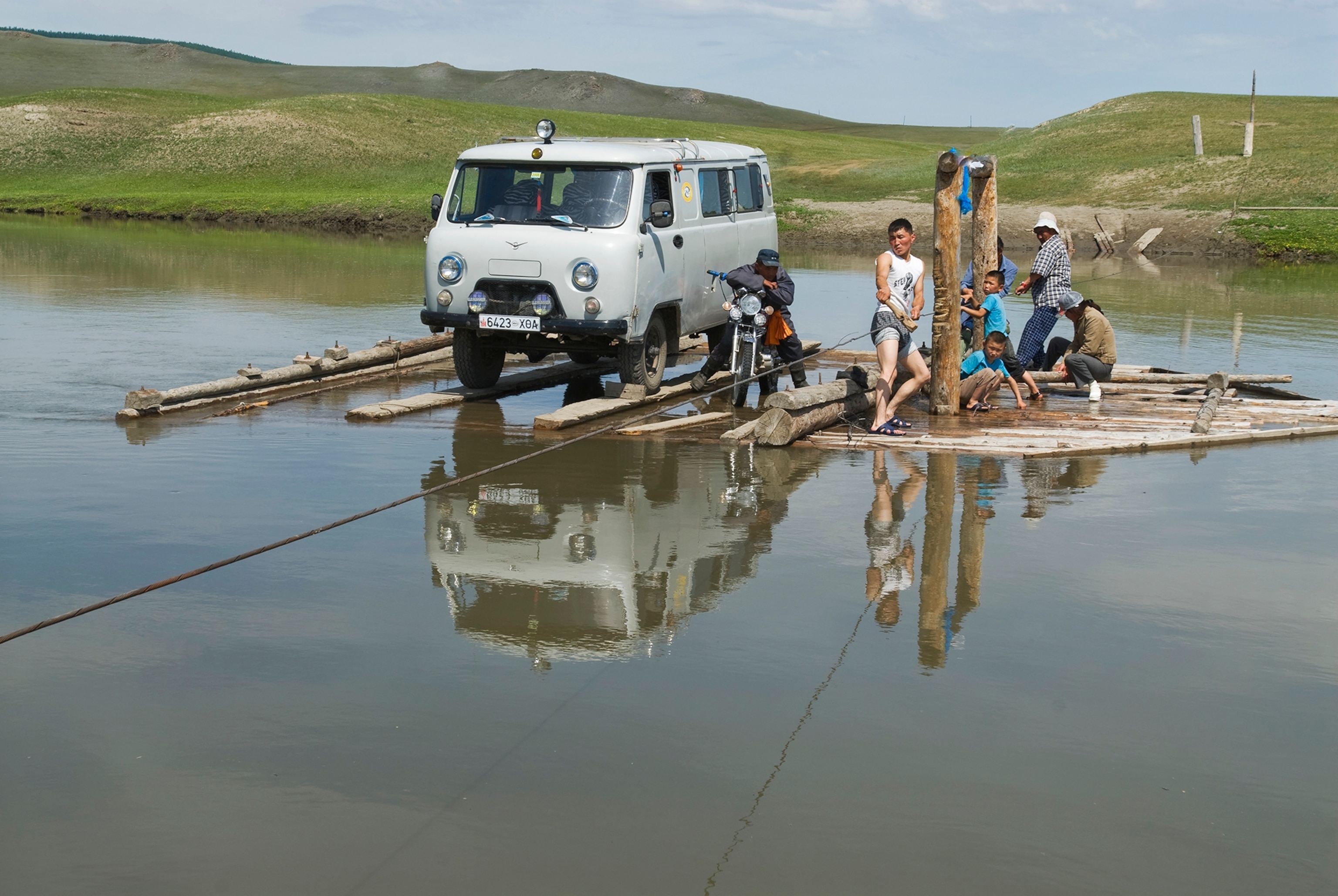 an archaeology expedition pulling a wooden ferry across a river